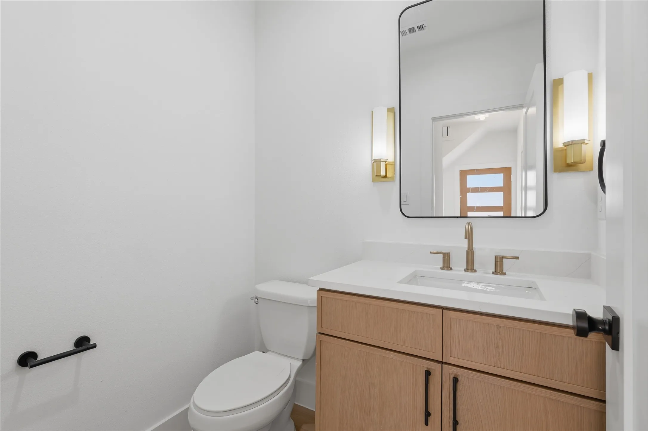 Wood-finish vanity with white countertop, undermount sink, and brass-finish faucet