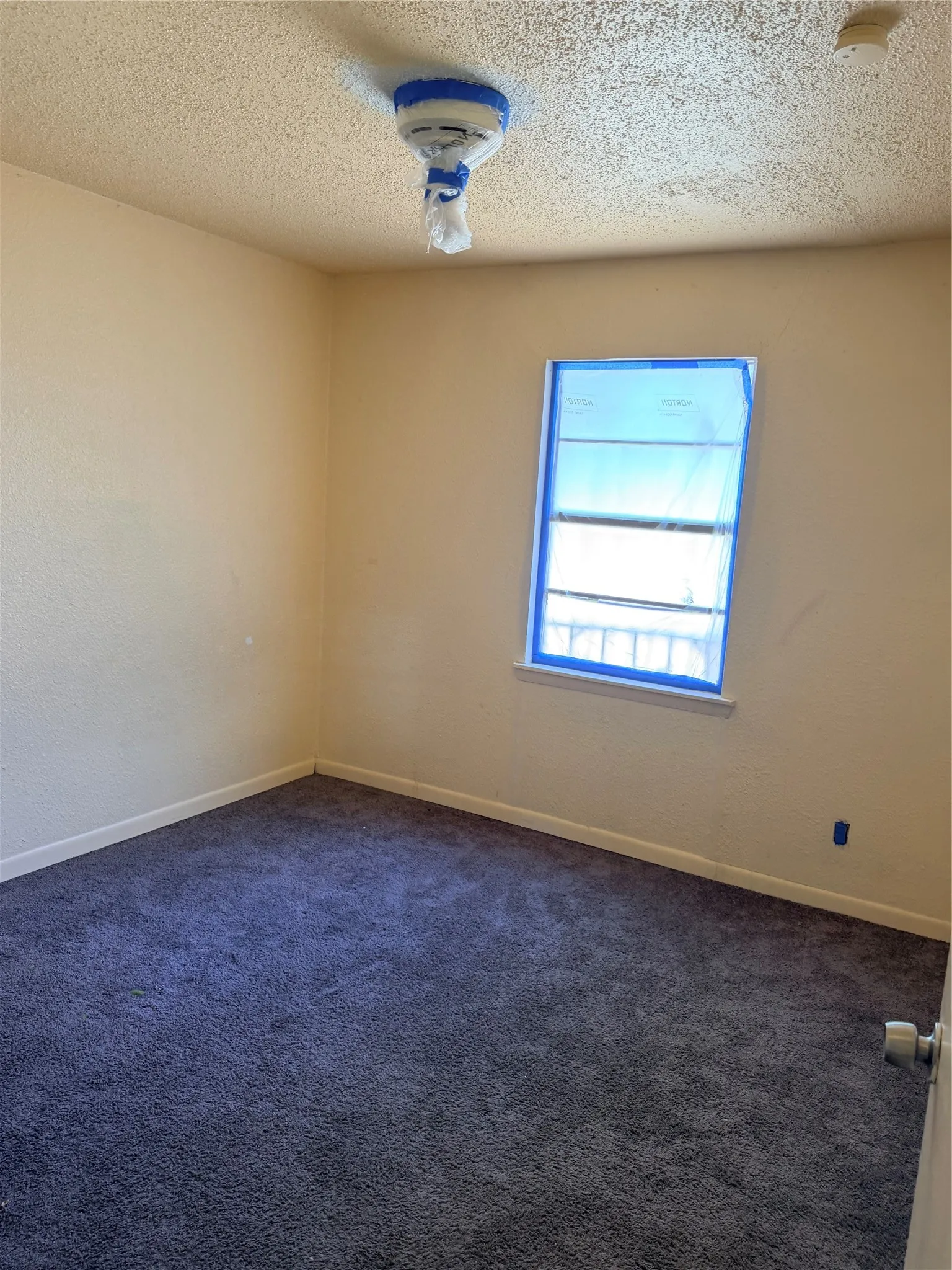 Carpeted flooring, painted walls, window opening, textured ceiling
