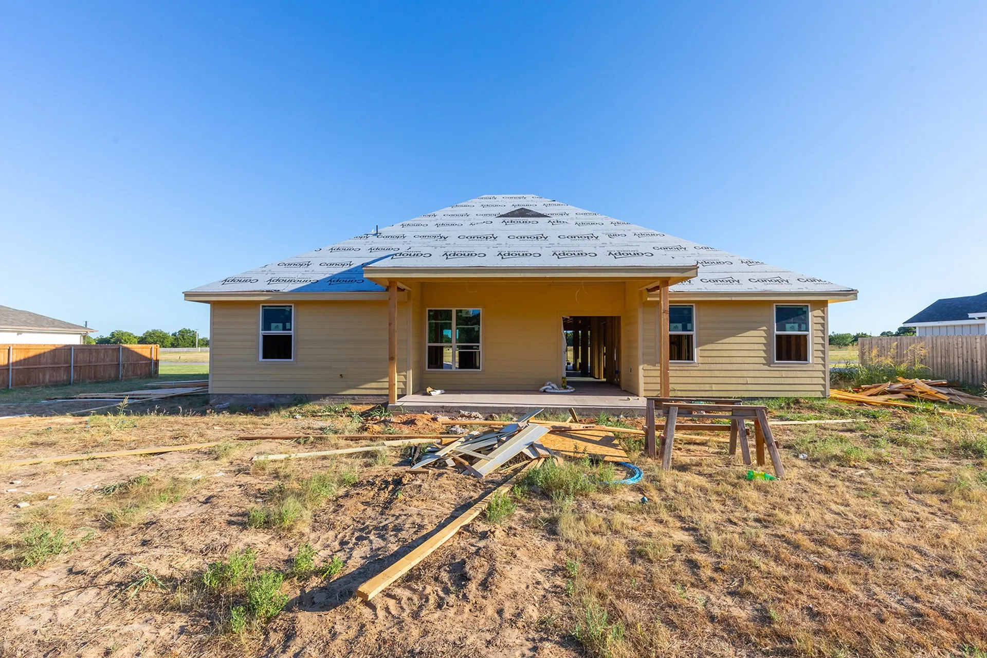 Rear exterior featuring a covered patio, multiple windows, and a low-pitched roof