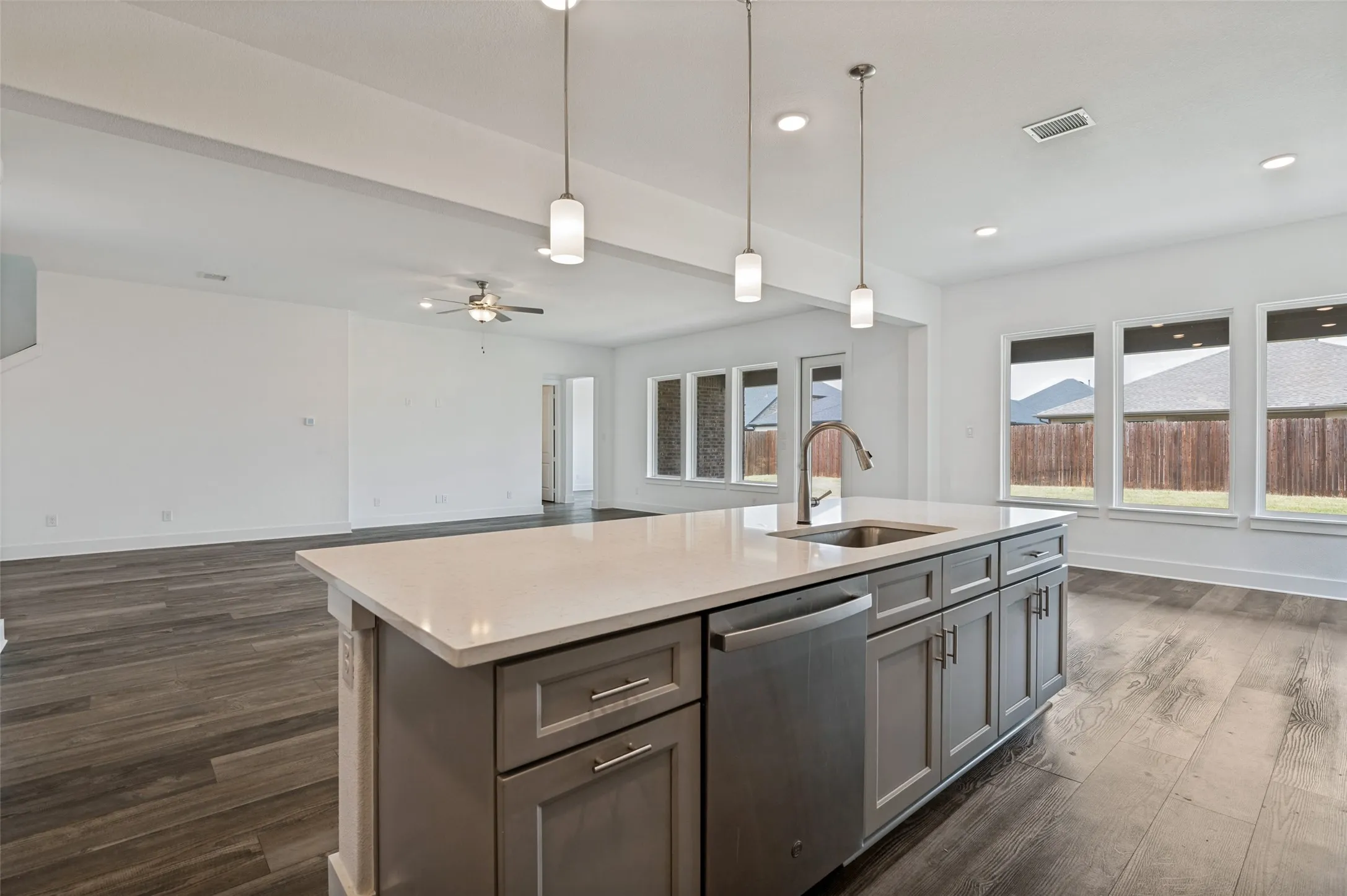 Kitchen island with a stainless steel sink, gooseneck faucet, and pendant lighting