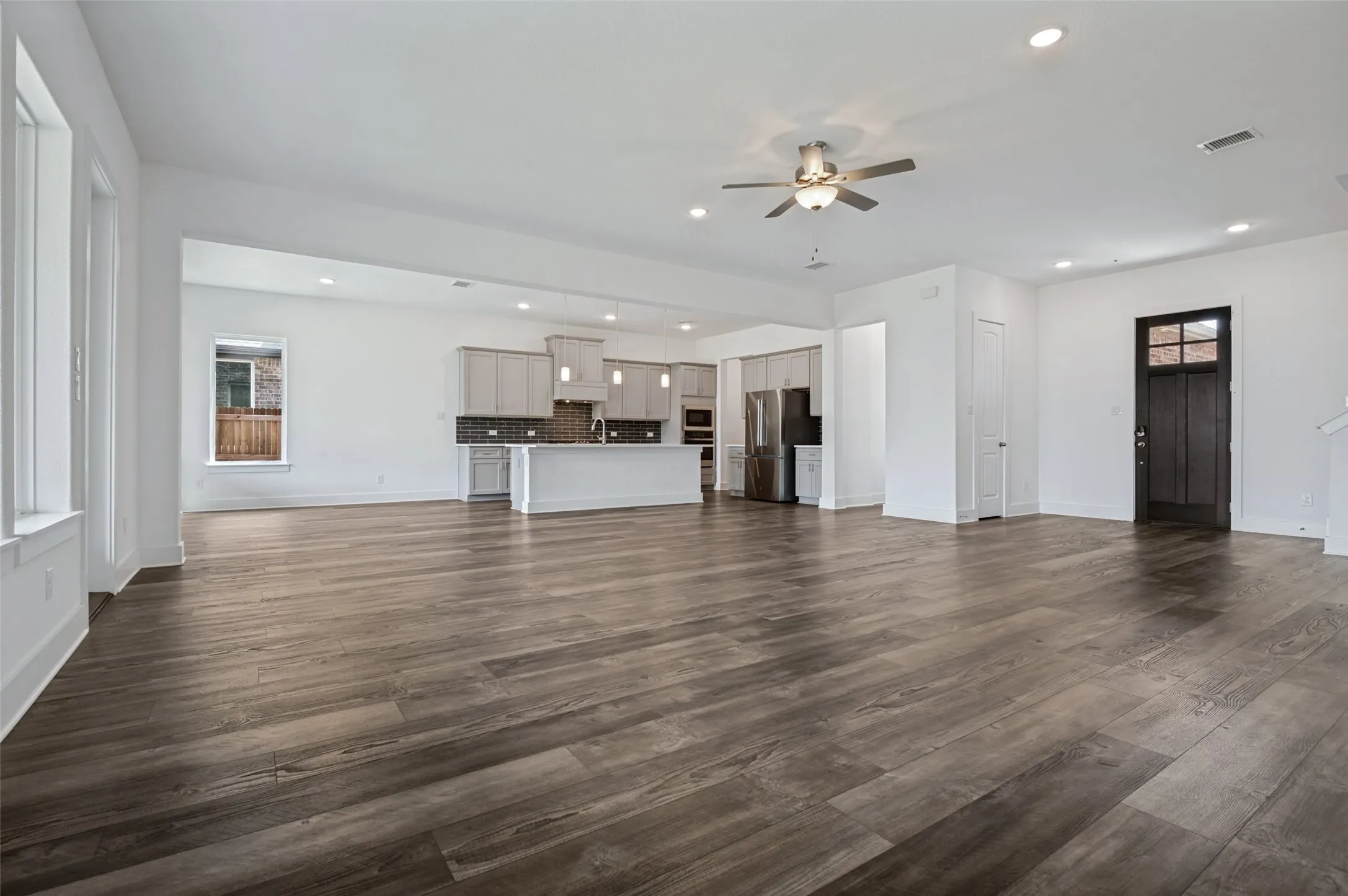 Open-concept living space featuring wood-finish flooring, recessed lighting, and a ceiling fan