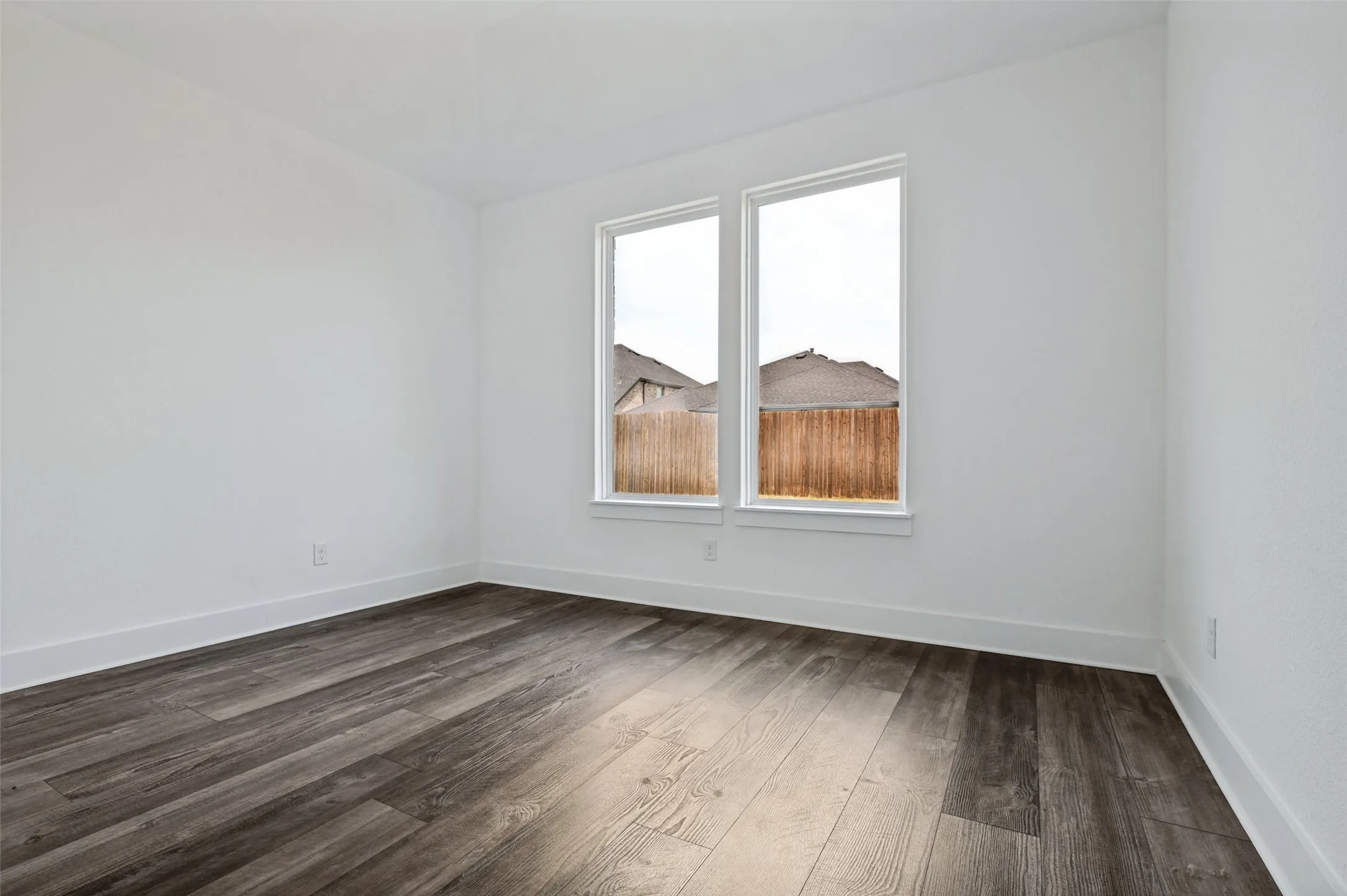 Two large windows, wood-finish flooring, white walls, and white trim