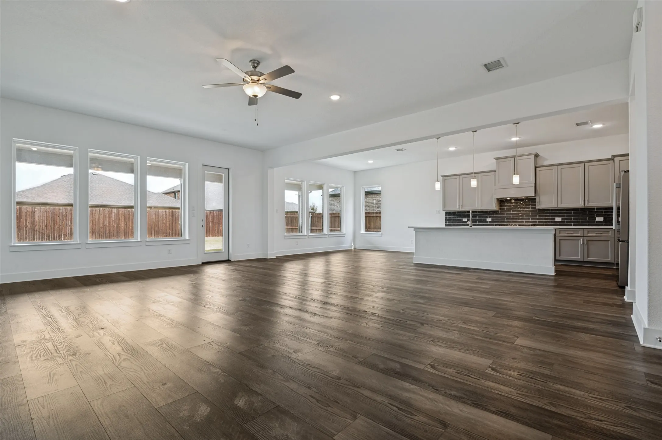 Expansive open-concept living area featuring wood-finish flooring, recessed lighting, and a ceiling fan