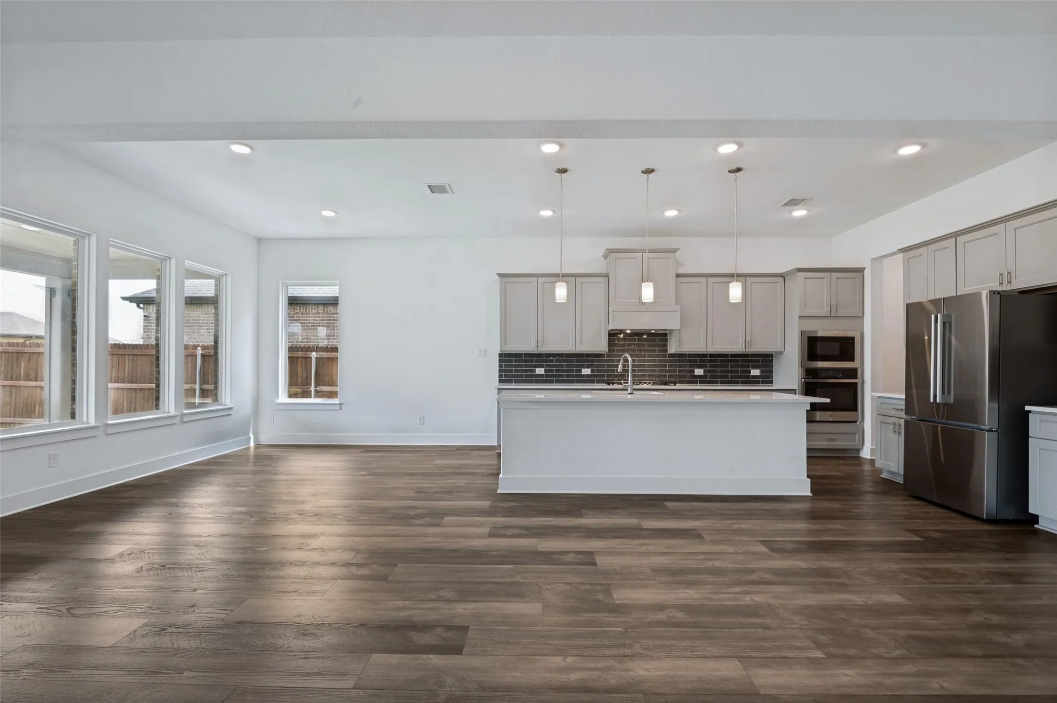 Open-concept living space featuring wood-finish flooring, recessed lighting, and multiple windows