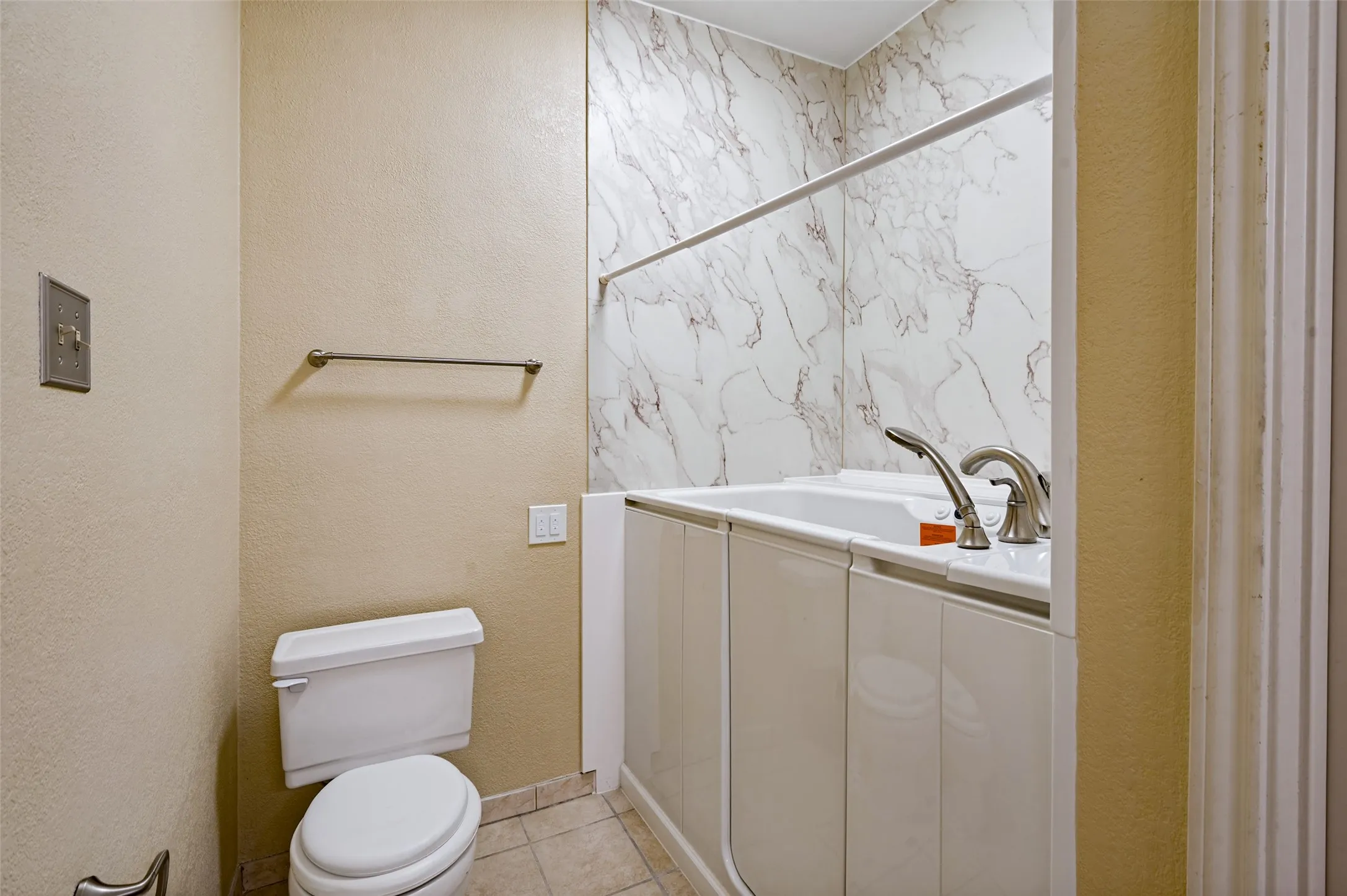 Bathroom featuring a white walk-in tub with brushed nickel fixtures and a white toilet