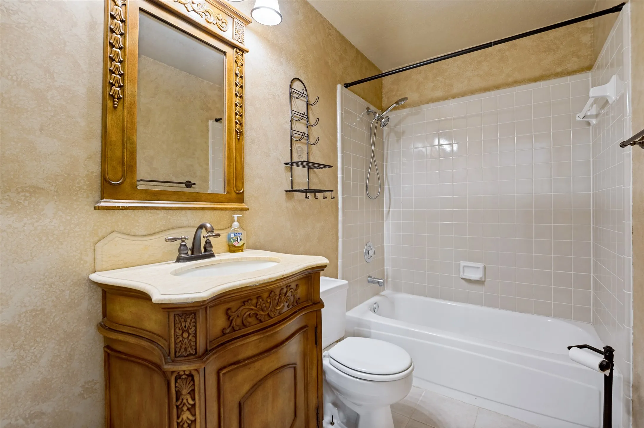 Ornate wood vanity with single basin sink, bronze-finish faucet, and coordinating framed mirror