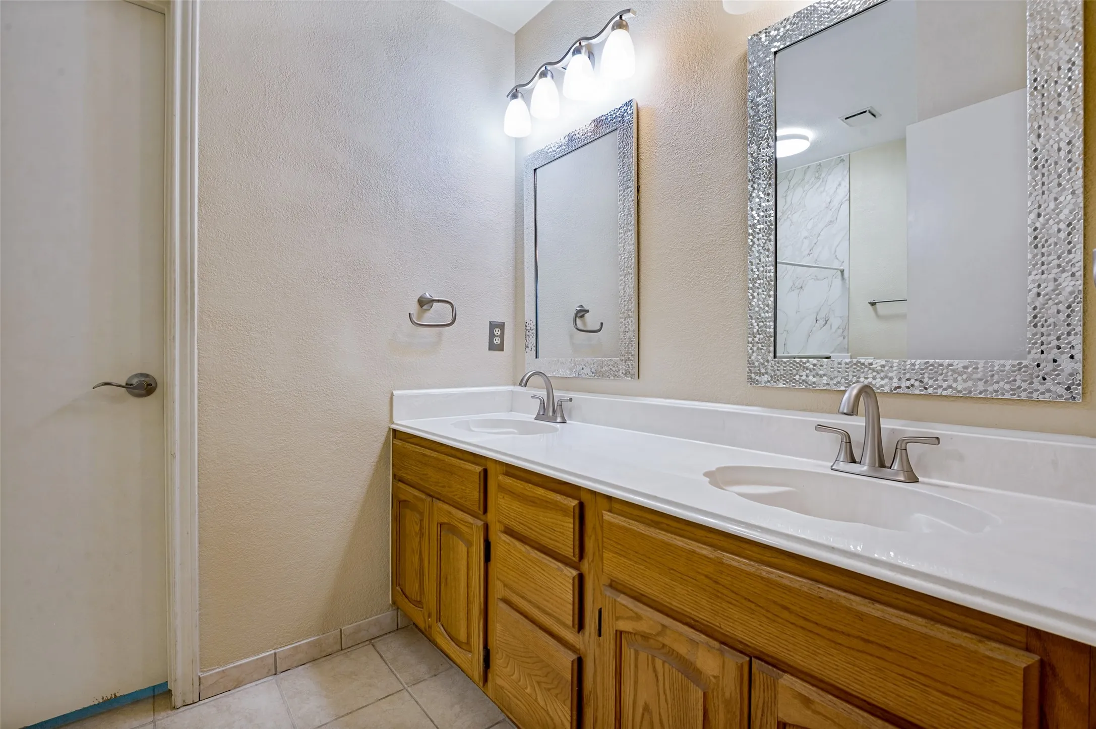 Dual-sink vanity with white quartz countertop, wood-finish cabinetry, and brushed nickel faucets