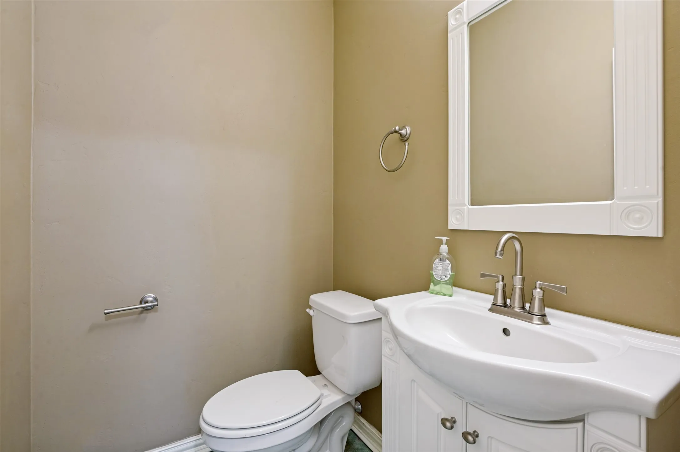 White vanity with integrated sink, brushed nickel faucet, and decorative framed mirror