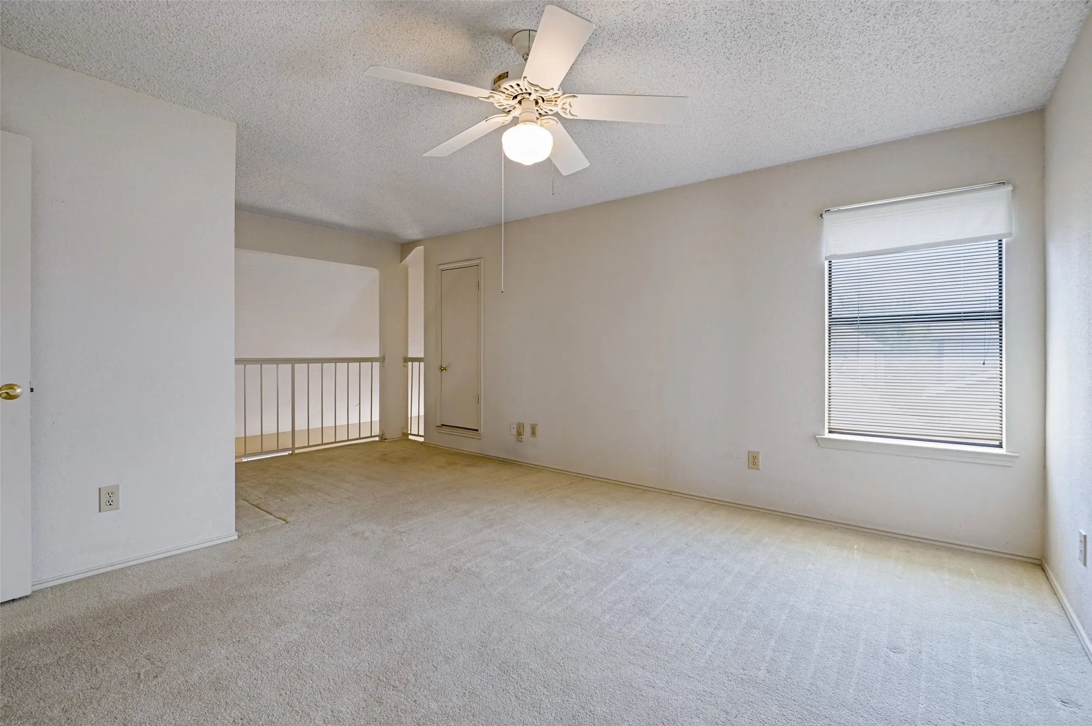 Carpeted room with a ceiling fan, a window with blinds, and a partial railing feature