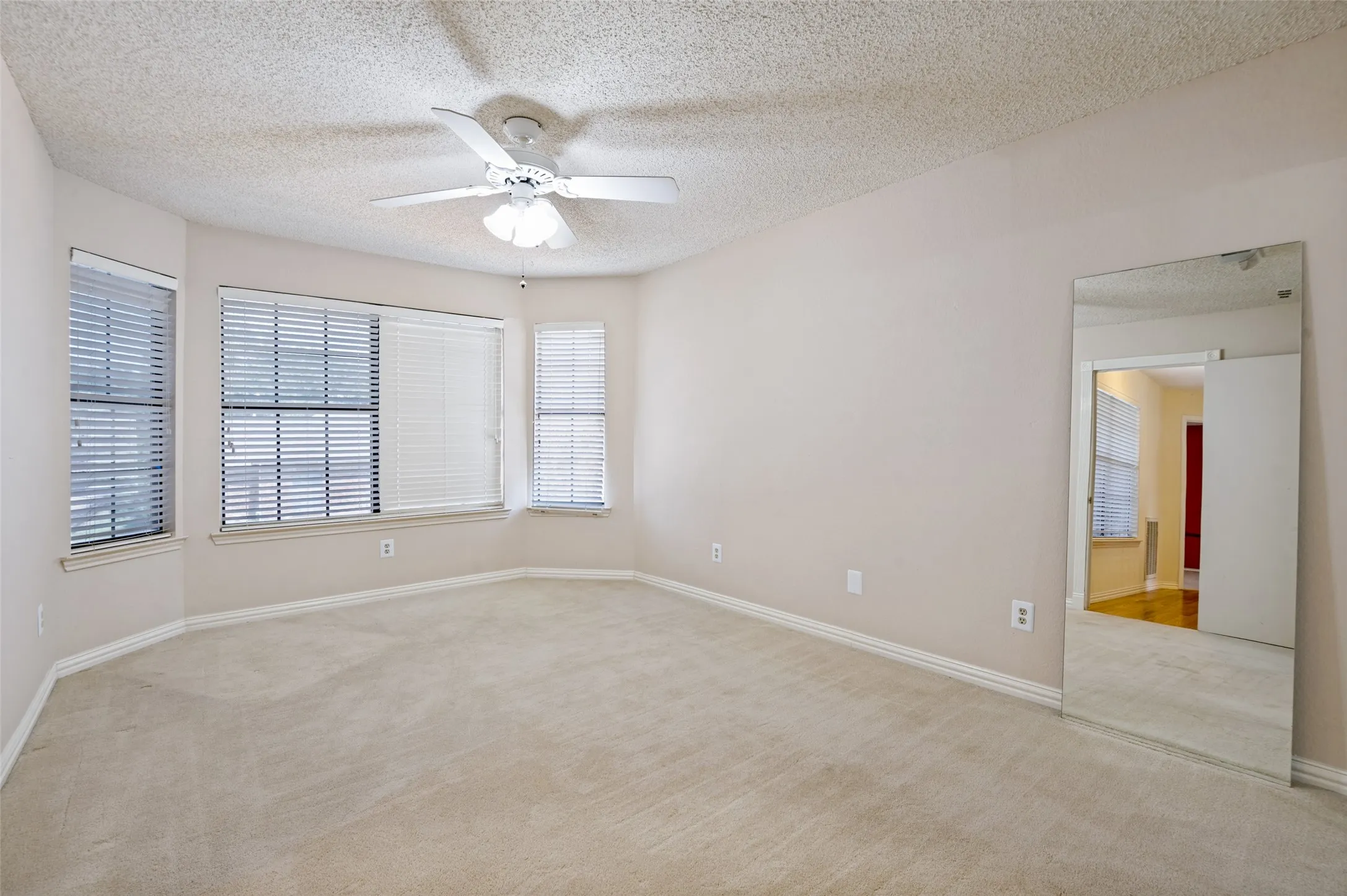 Recessed window alcove with three windows, textured ceiling, and a ceiling fan with integrated lighting