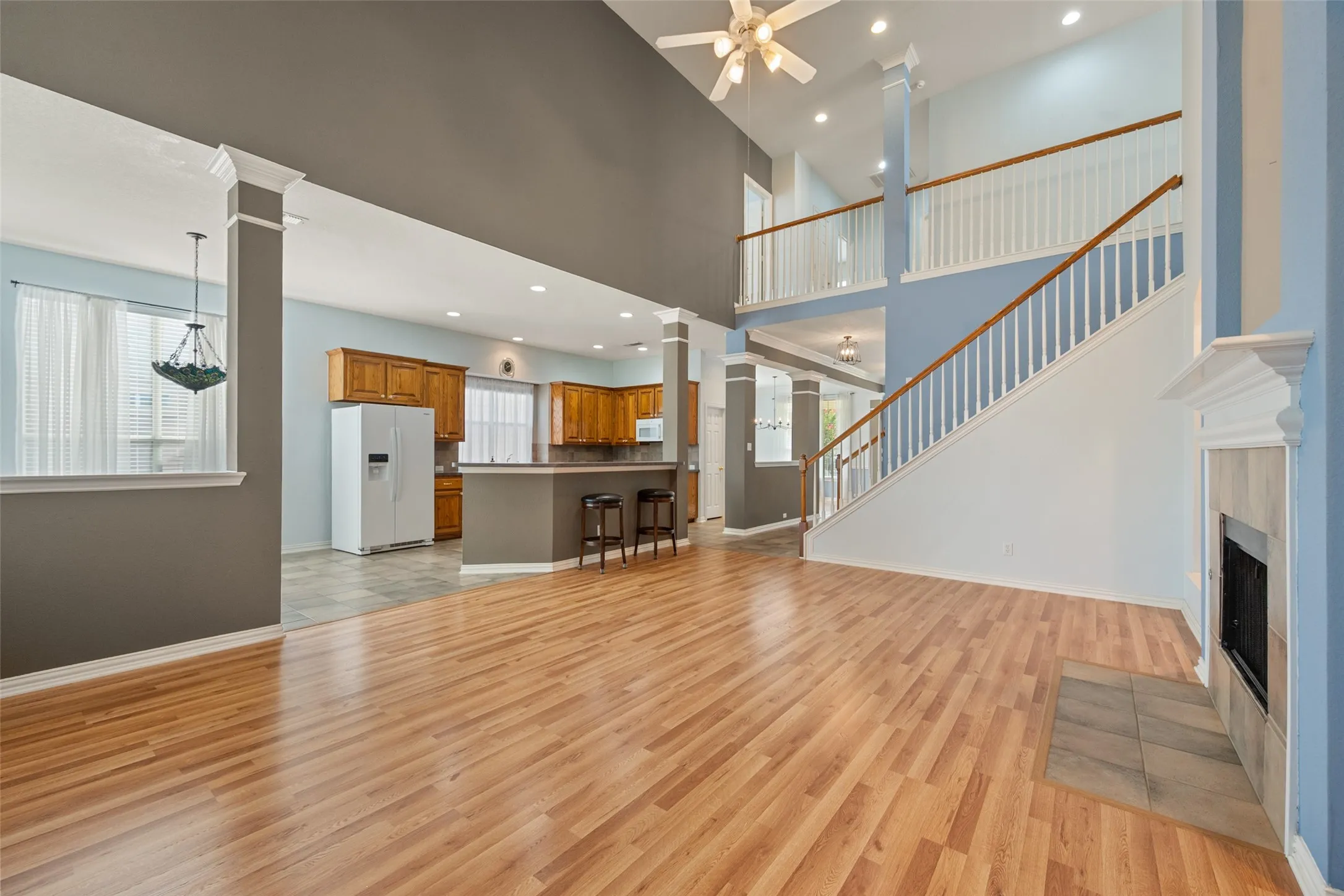 Spacious living area featuring wood-finish flooring, a fireplace with tile surround, and a ceiling fan