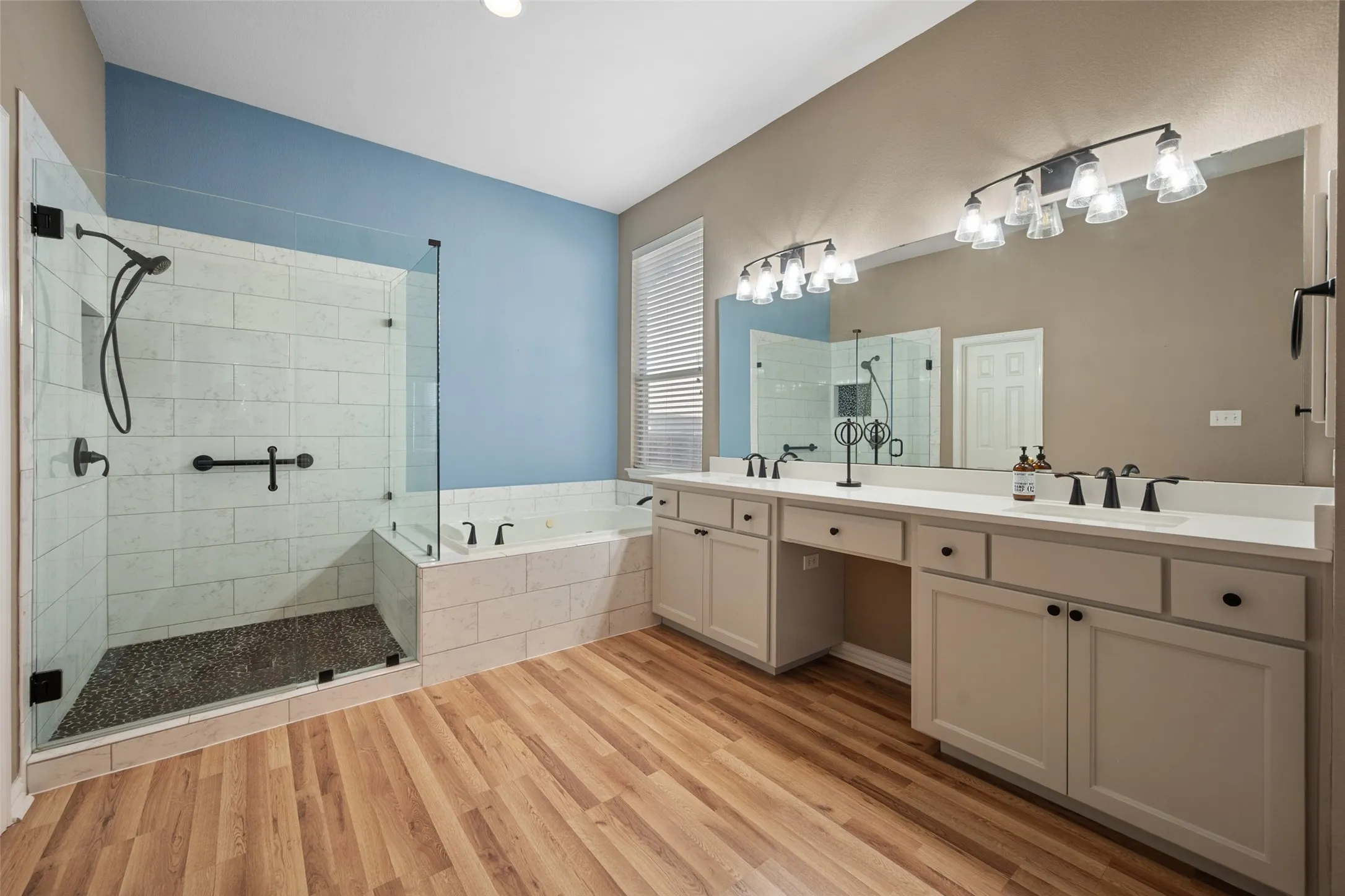 Primary bath has been updated. Walk-in shower with clear glass enclosure and pebble flooring, built-in bathtub, dual vanity with undermount sinks, wood-finish flooring and a huge walk in closet not shown
