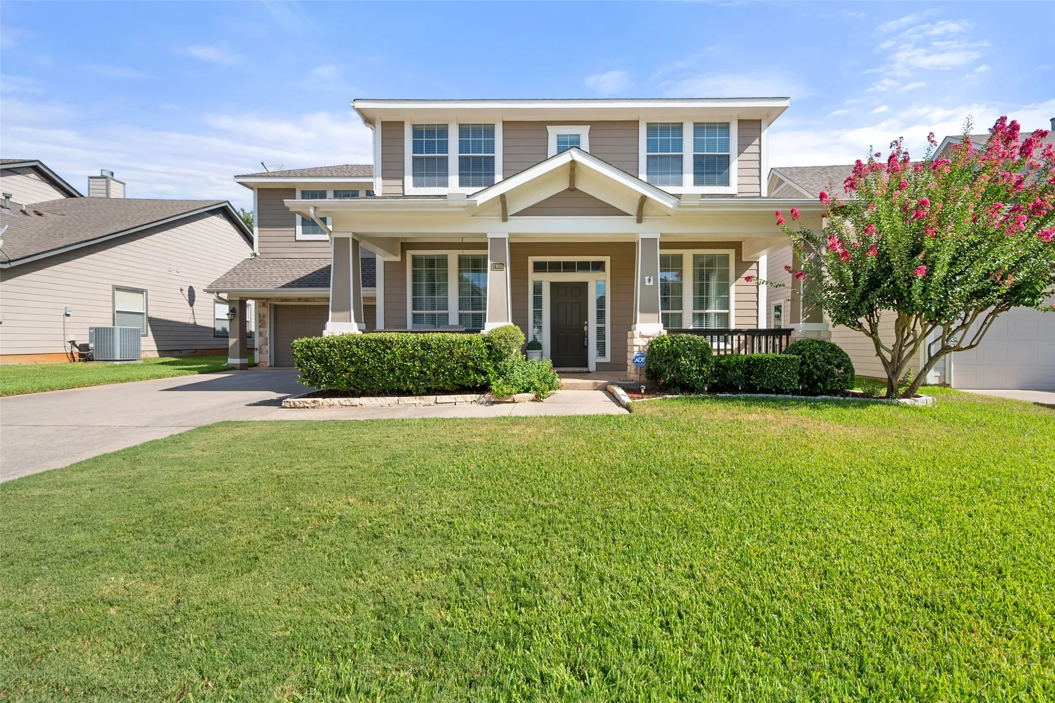 Two-story residence featuring a covered front porch, a two-car garage, and a manicured lawn