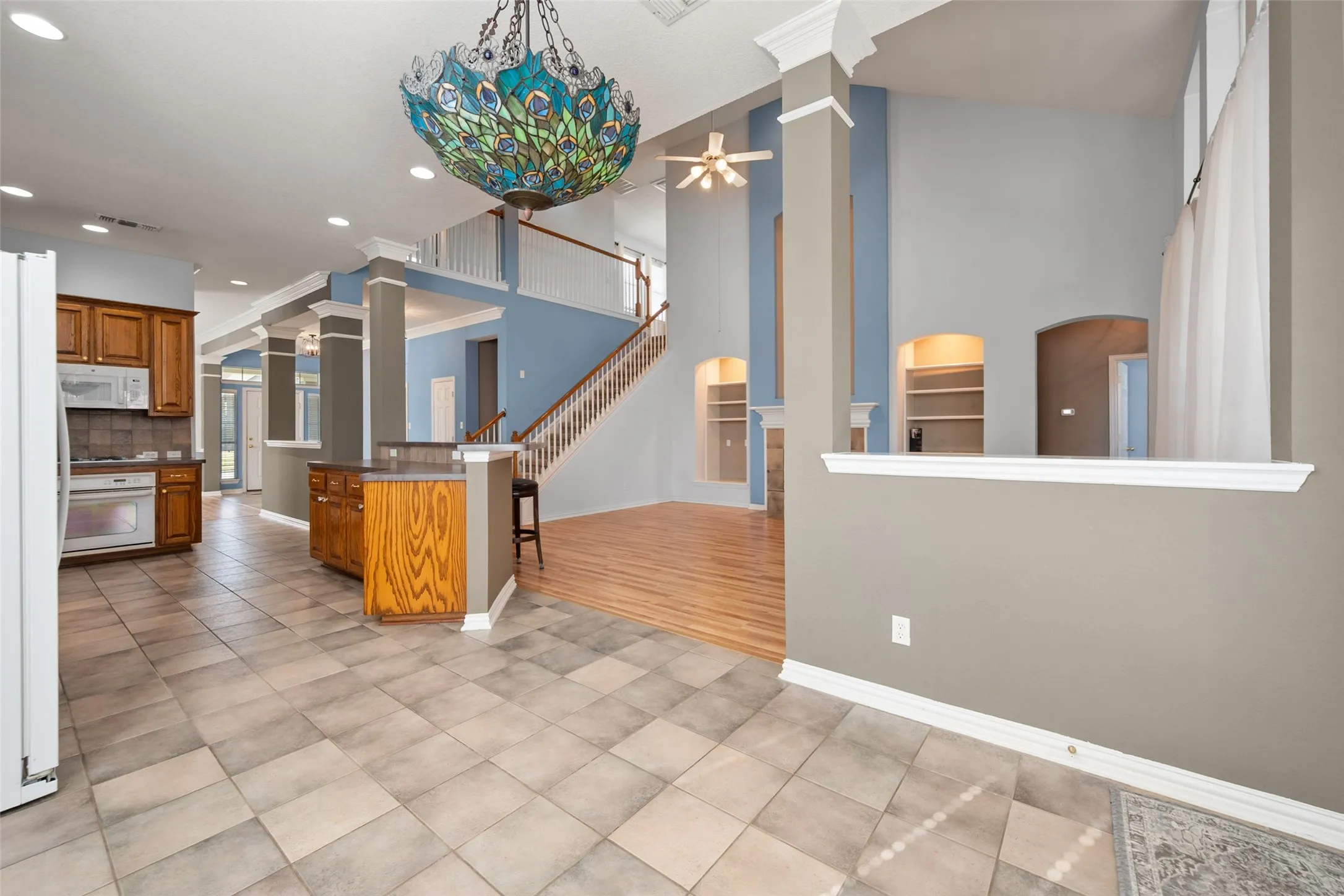 Vaulted ceilings, a decorative chandelier, a staircase with wood treads, built-in shelving, and tile flooring