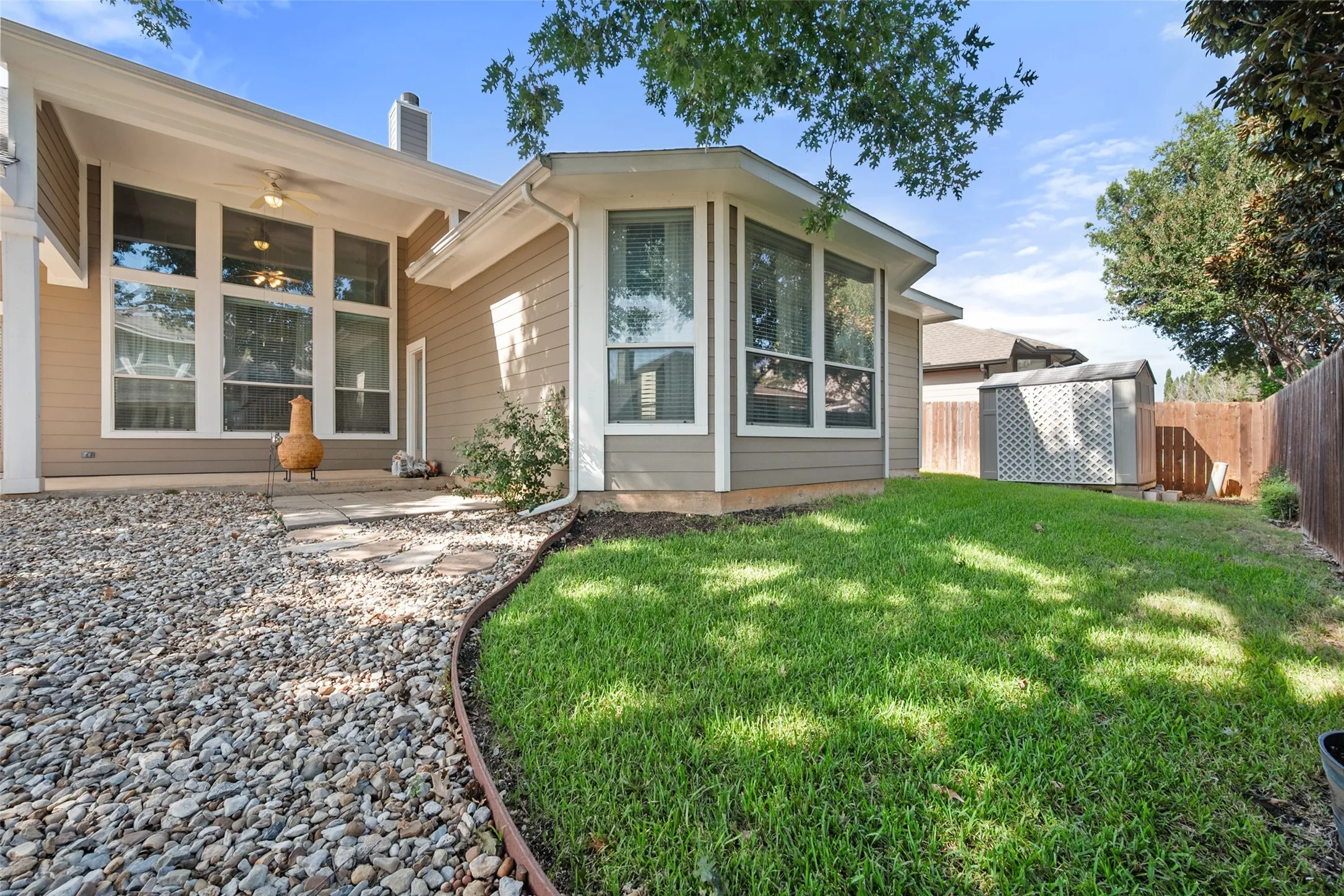 Expansive backyard featuring a manicured lawn, established landscaping, and a wooden privacy fence along with a storage shed for the tools
