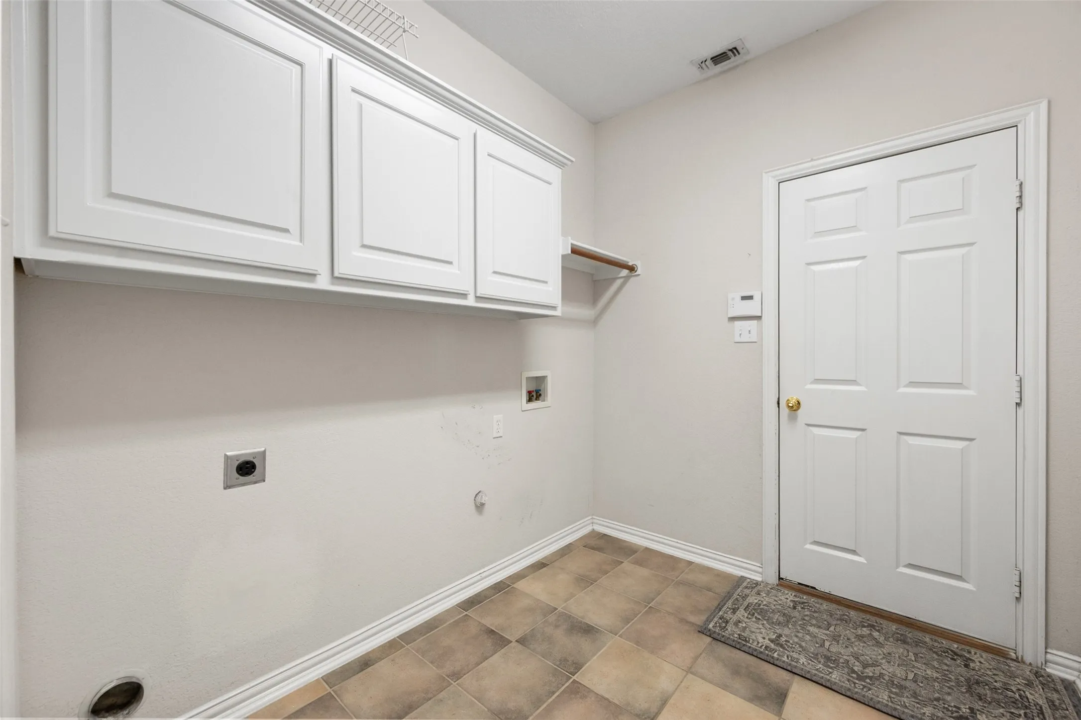 White shaker-style cabinetry, a built-in hanging rod, tiled flooring