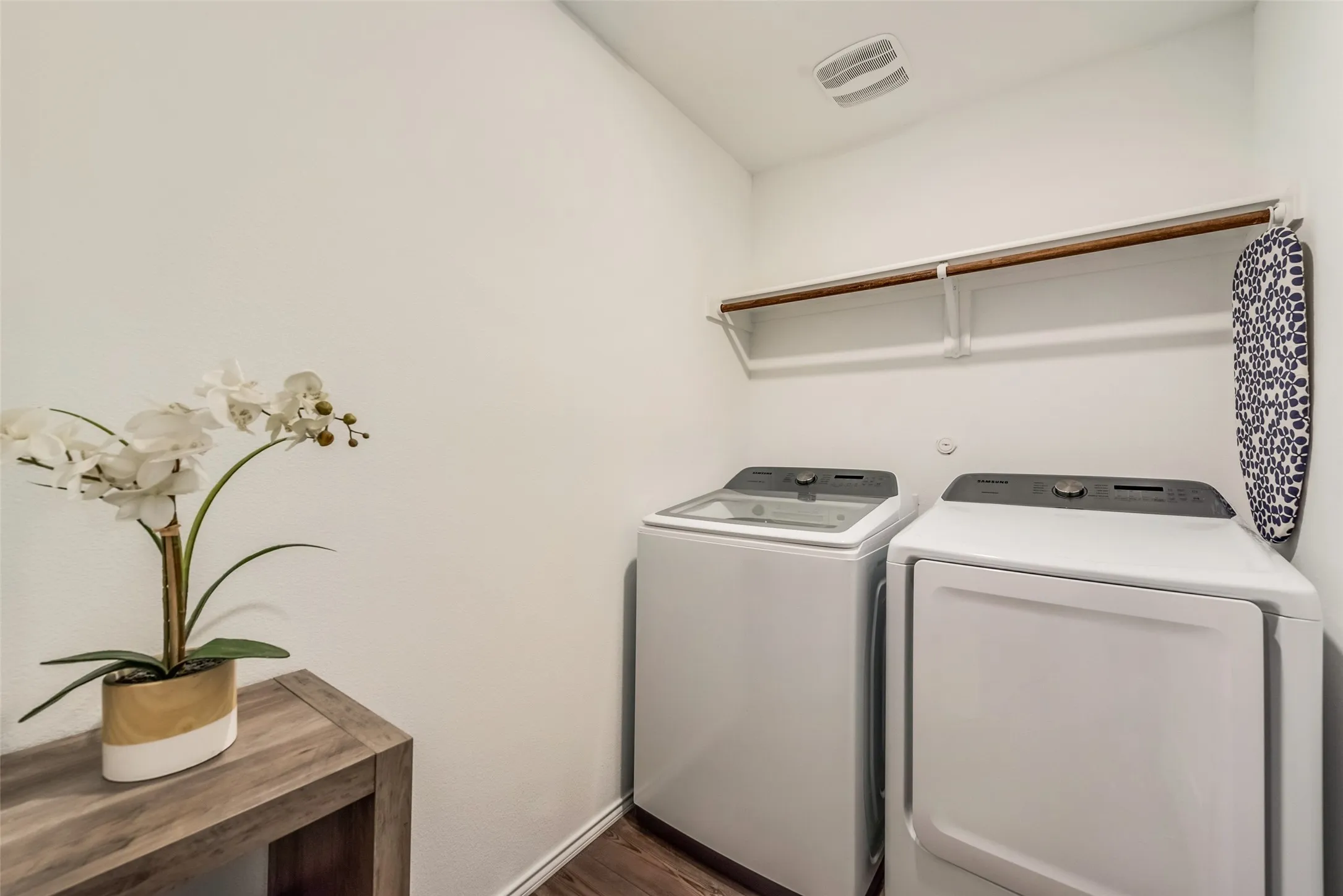Laundry area featuring a top-load washing machine, front-load dryer, and a built-in hanging rod