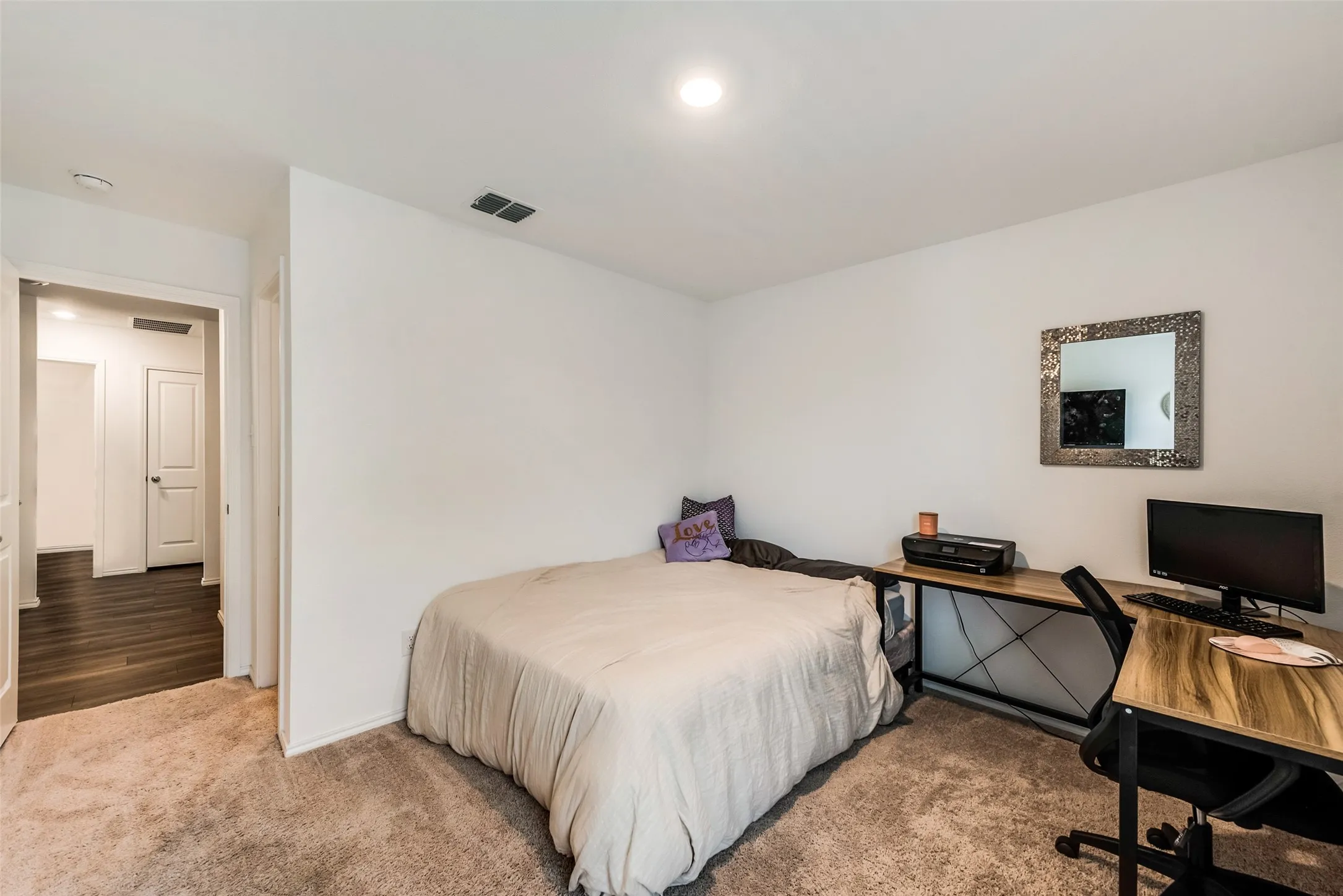Recessed ceiling lighting illuminates the room with neutral wall tones and plush carpet flooring