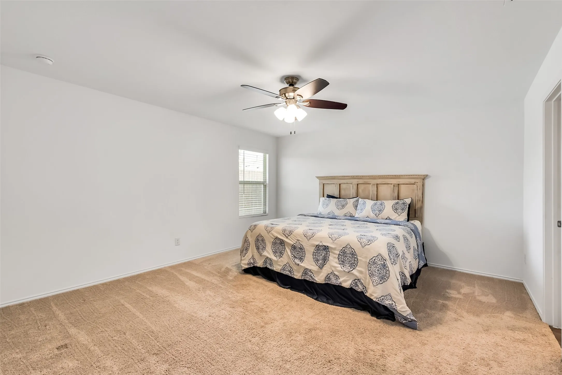 Carpeted flooring, ceiling fan with integrated lighting, window with blinds, white walls, and a door frame