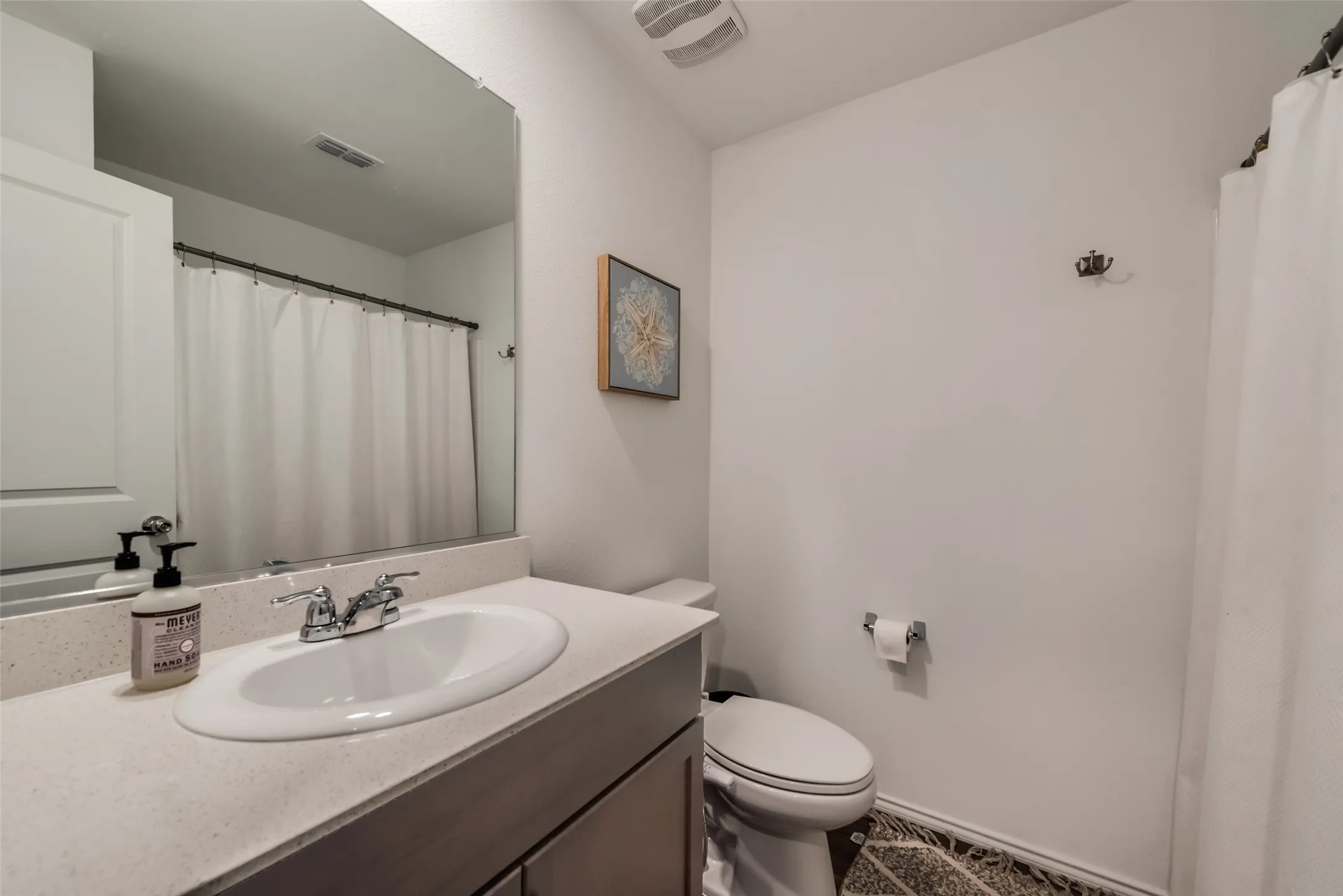 Vanity with an integrated sink, polished chrome faucet, and expansive mirror
