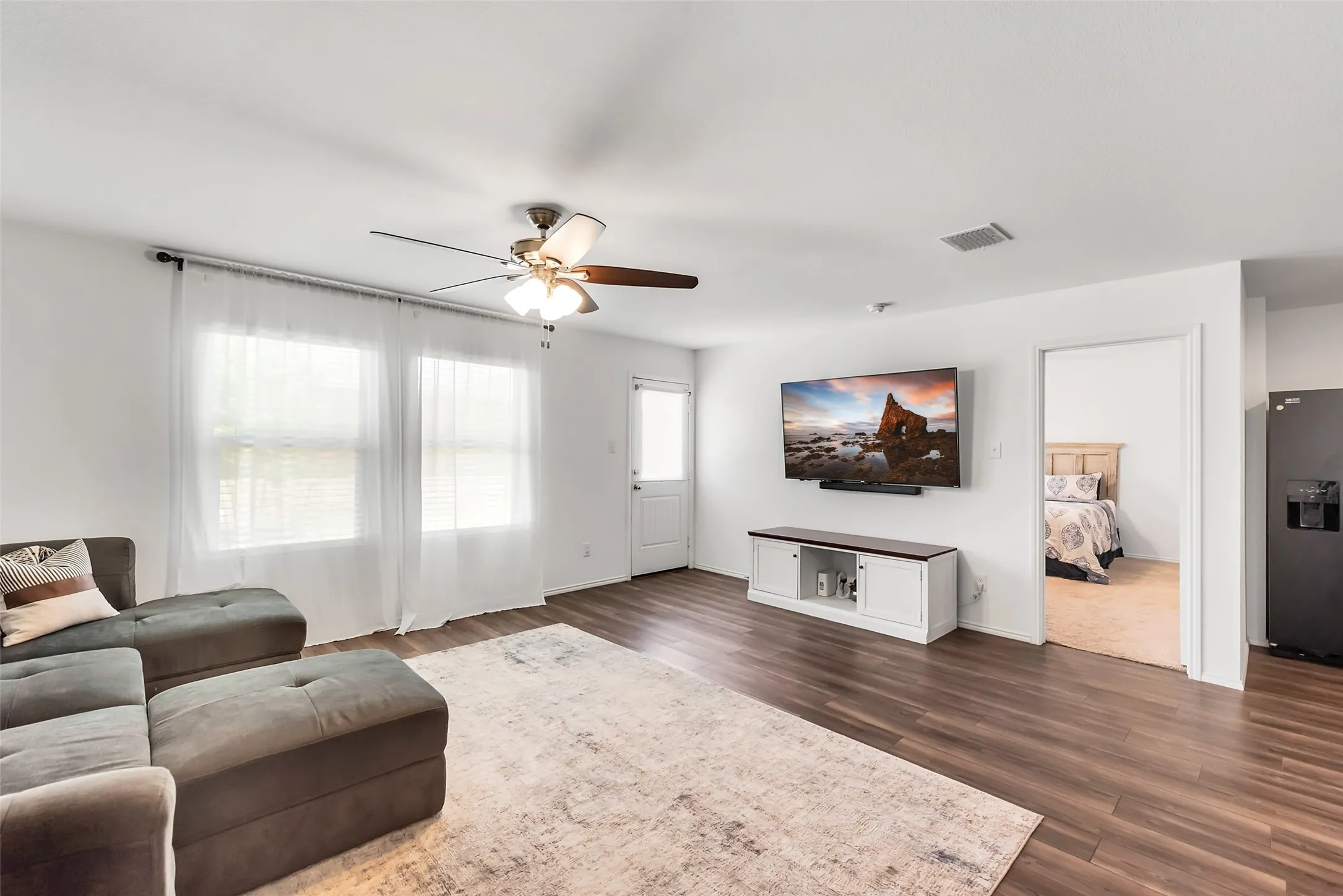 Wood-finish flooring throughout, white walls, and a ceiling fan with light fixture