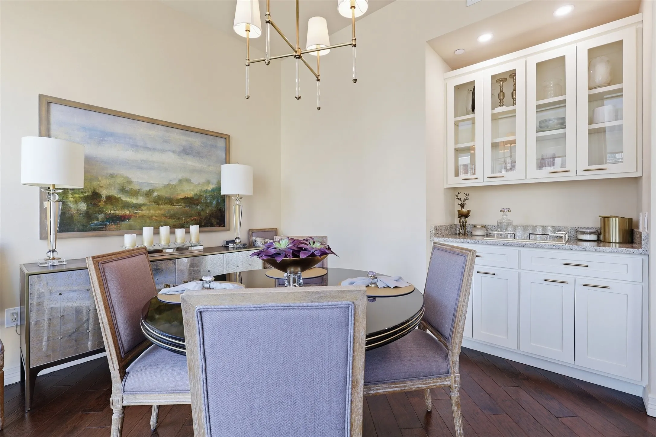 Built-in cabinetry with glass-front uppers and a light-toned countertop, wood-finish flooring, and a chandelier with decorative accents