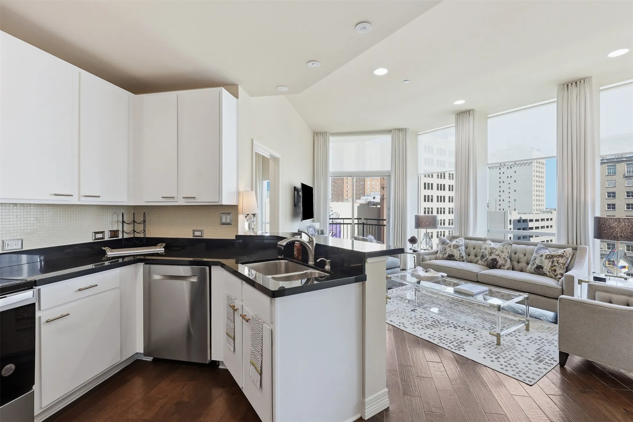 Full-height windows with roller shades, recessed lighting, wood-finish flooring, white cabinetry, and a stainless steel dishwasher