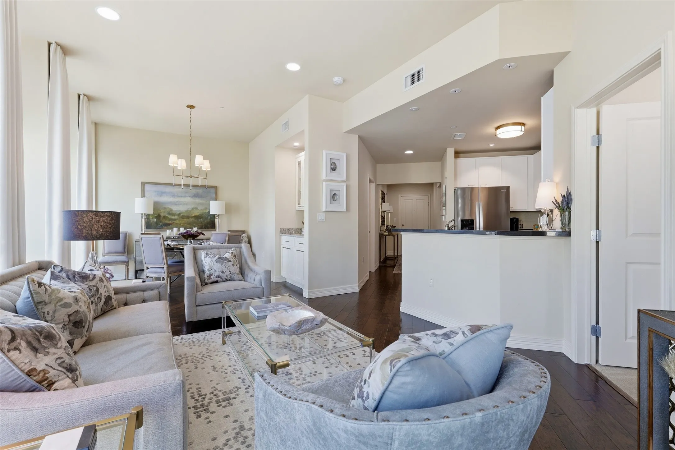 Expansive wood-finish flooring throughout, with recessed lighting and a built-in kitchen peninsula with a dark countertop