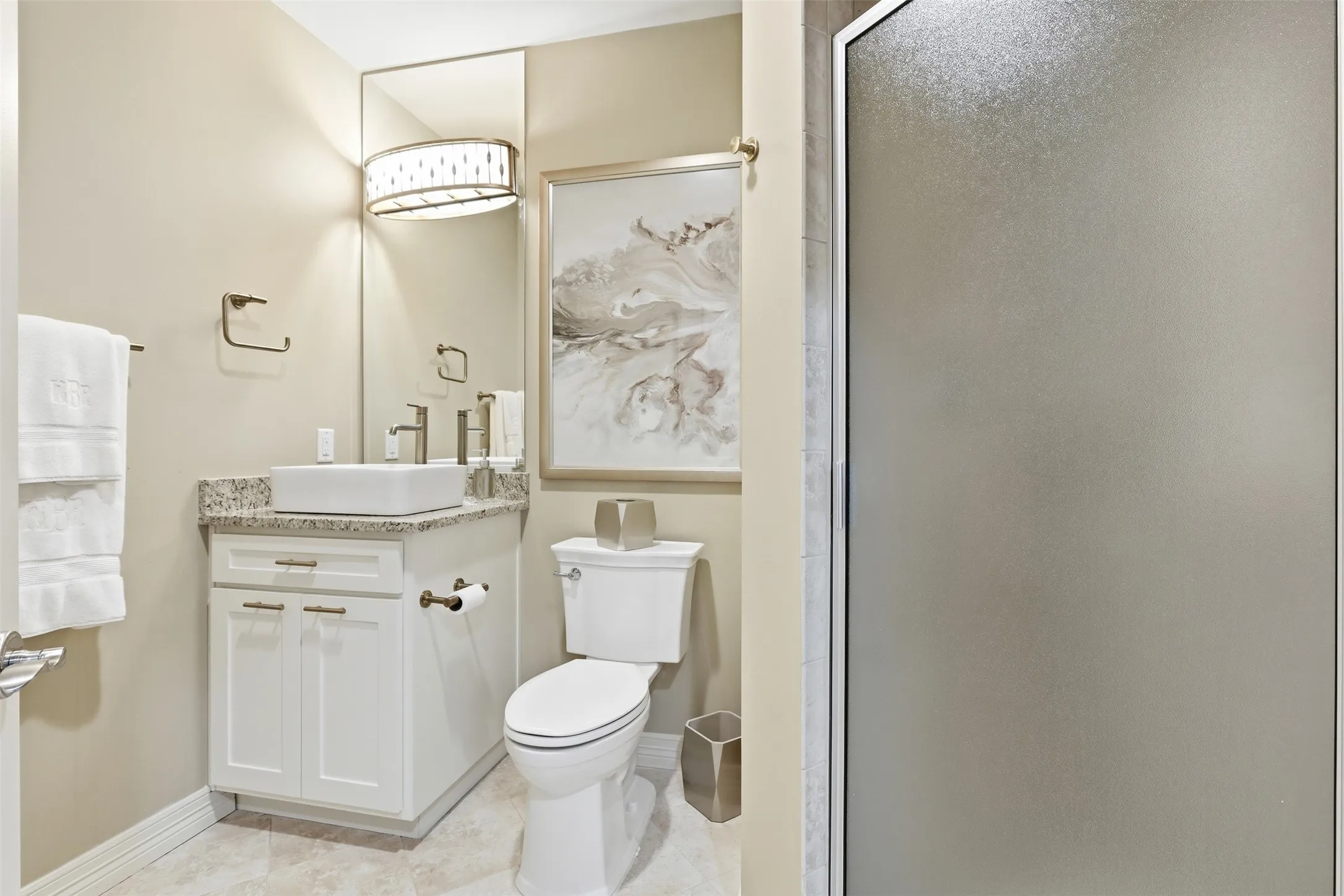White vanity with a vessel sink and granite countertop