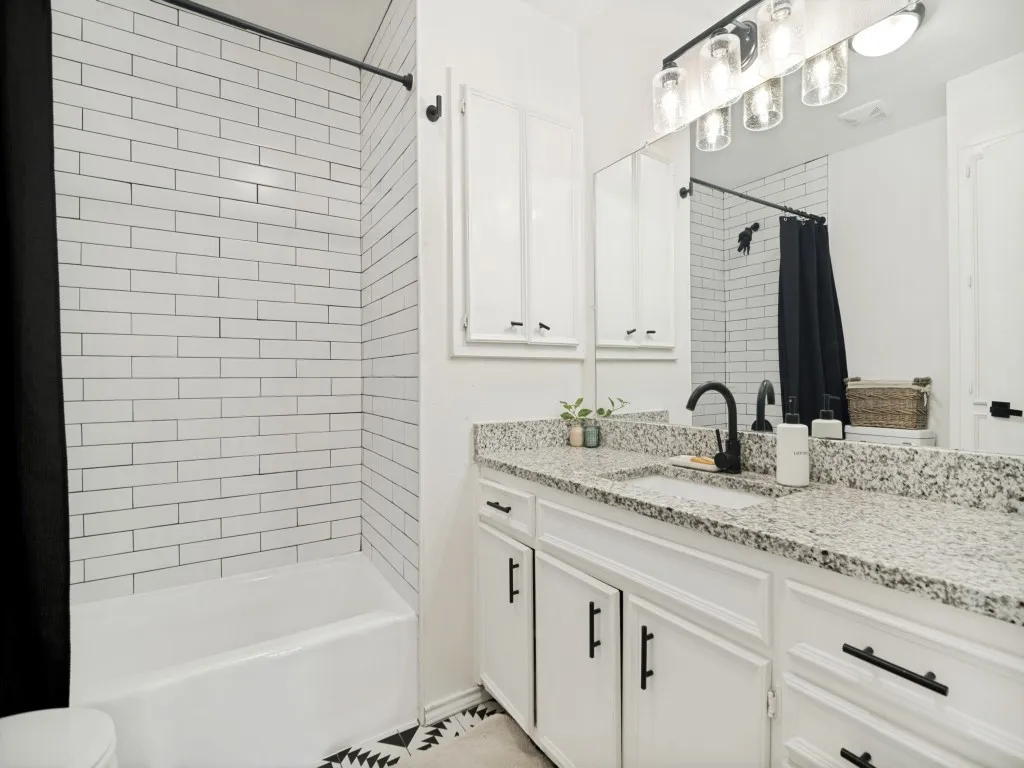 Second full bath in the home has granite top and tiled combination tub and shower.