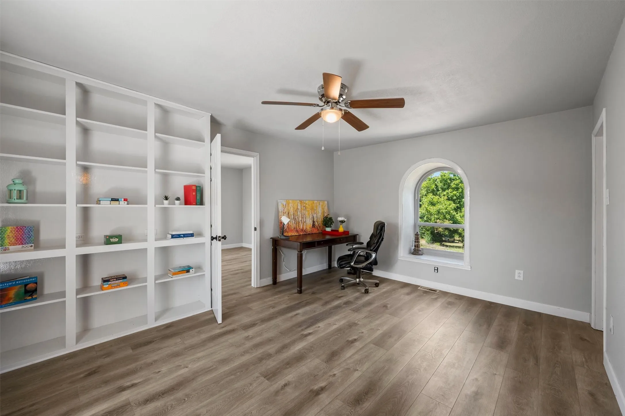 Office or additional living area with built-in shelving and ceiling fan.