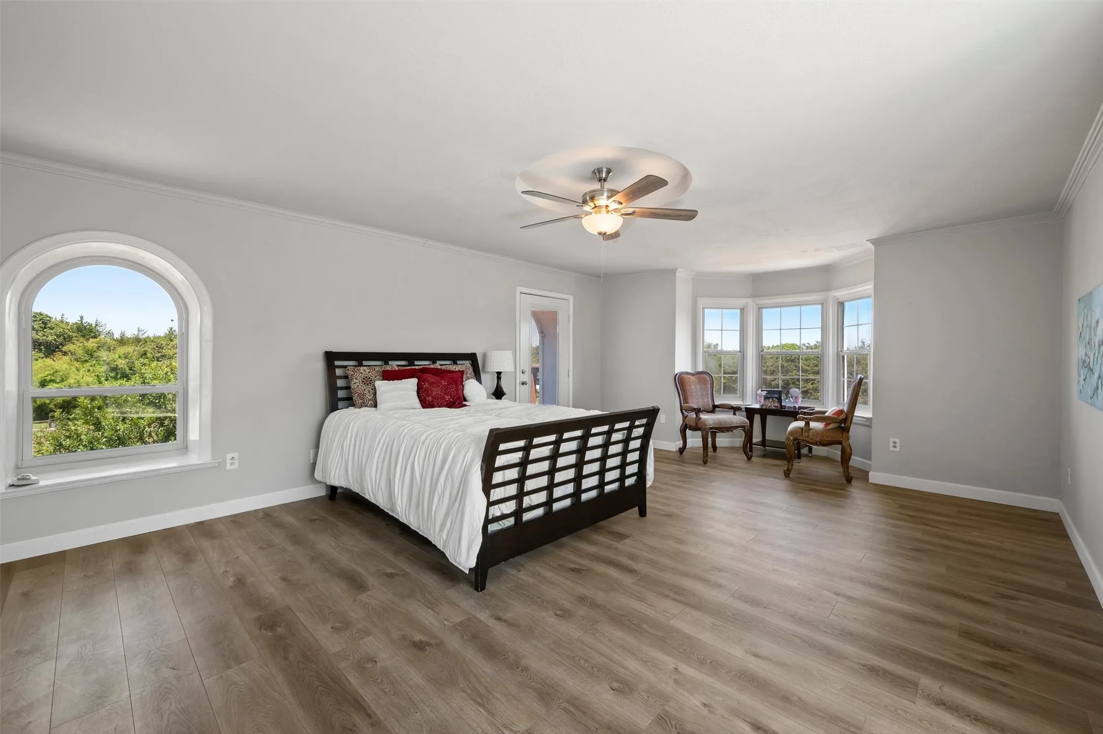 Large primary bedroom with bay window, walk-in closet, ceiling fan, and balcony access with expansive views.