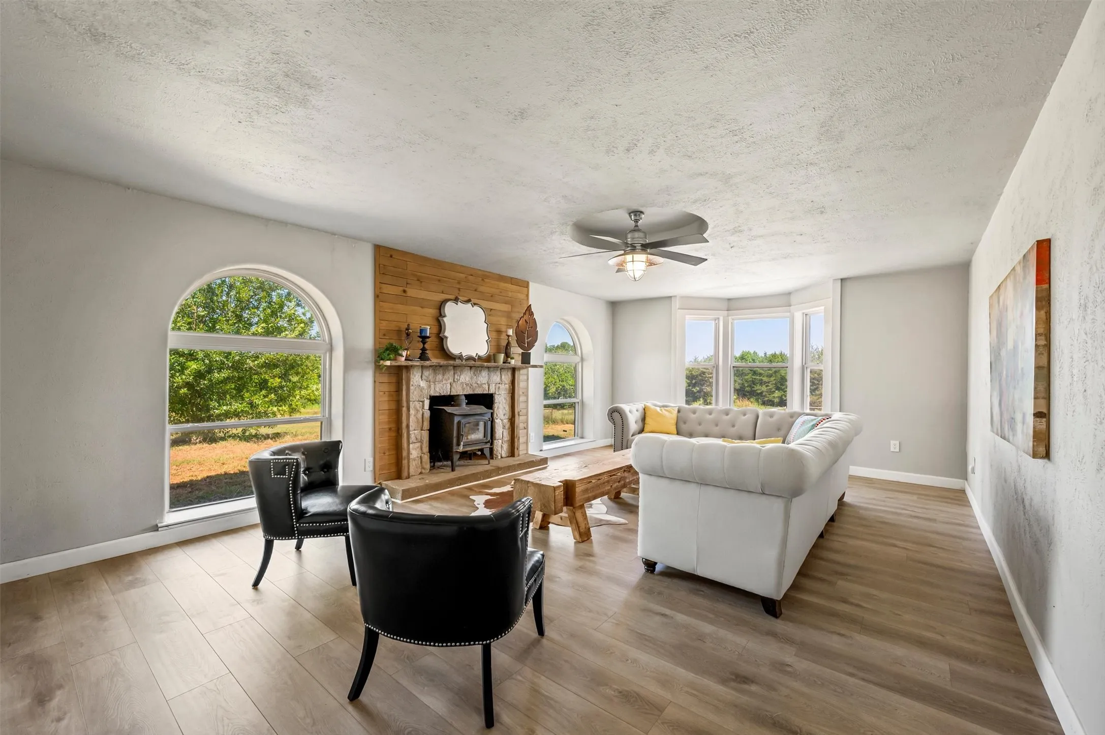 Spacious living room with fireplace, ceiling fan, and luxury vinyl flooring.