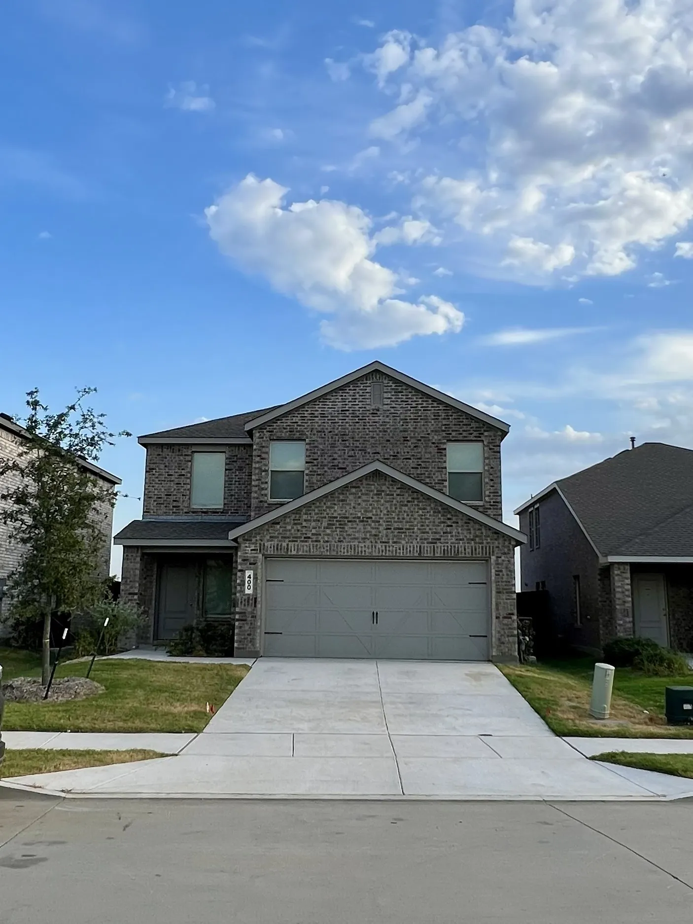 Classic two-story brick residence featuring a clean driveway approach, oversized garage with paneled doors, and manicured front lawn