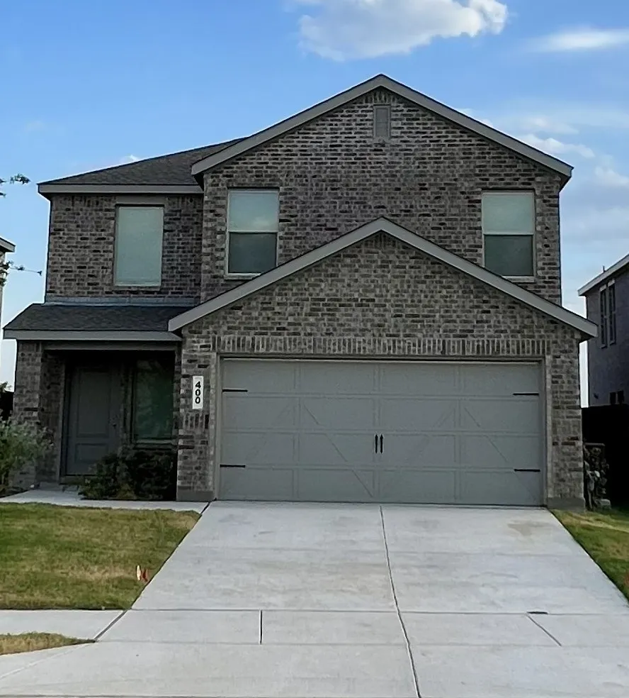 Brick exterior construction with a two-story design, attached two-car garage, covered entry, and a concrete driveway
