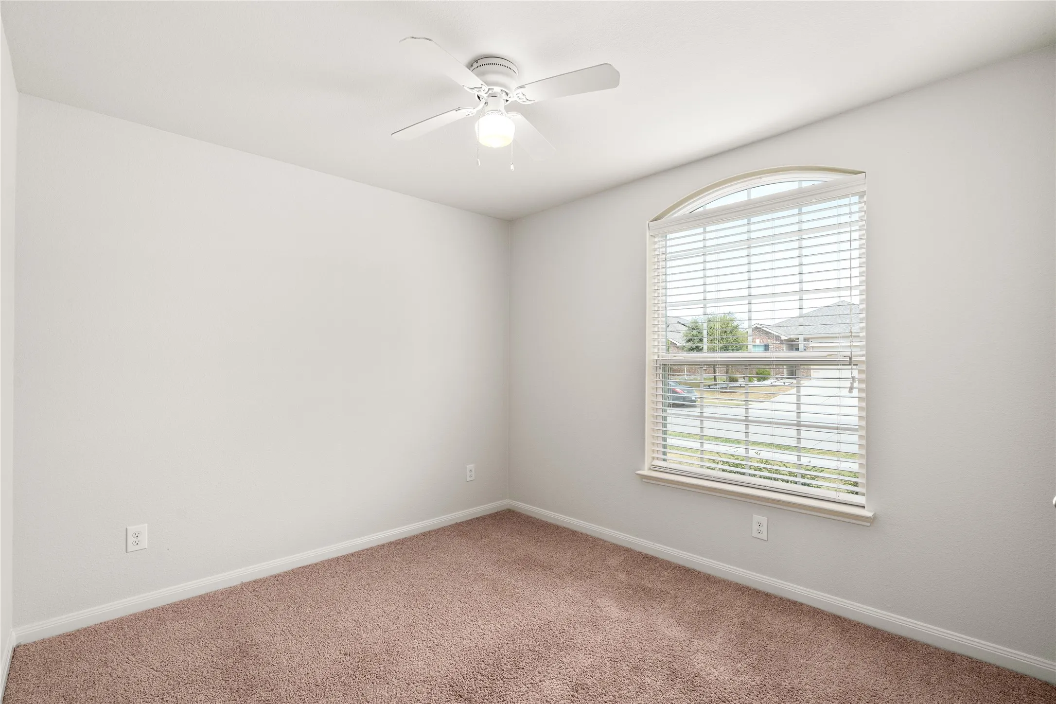 Arched window with blinds, ceiling fan, and light-colored carpet