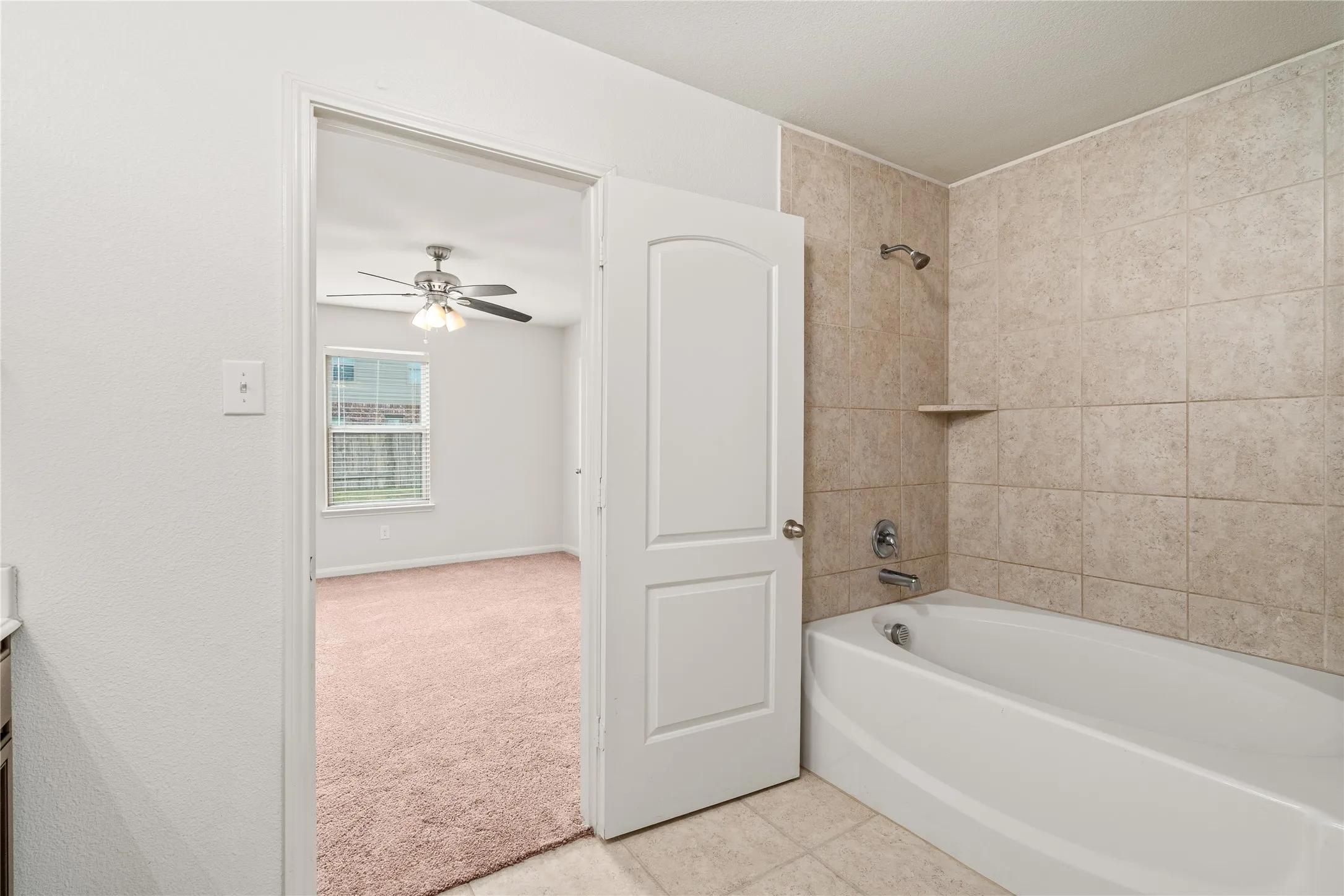 Tub and shower combination with tiled surround, shower shelf, and chrome fixtures