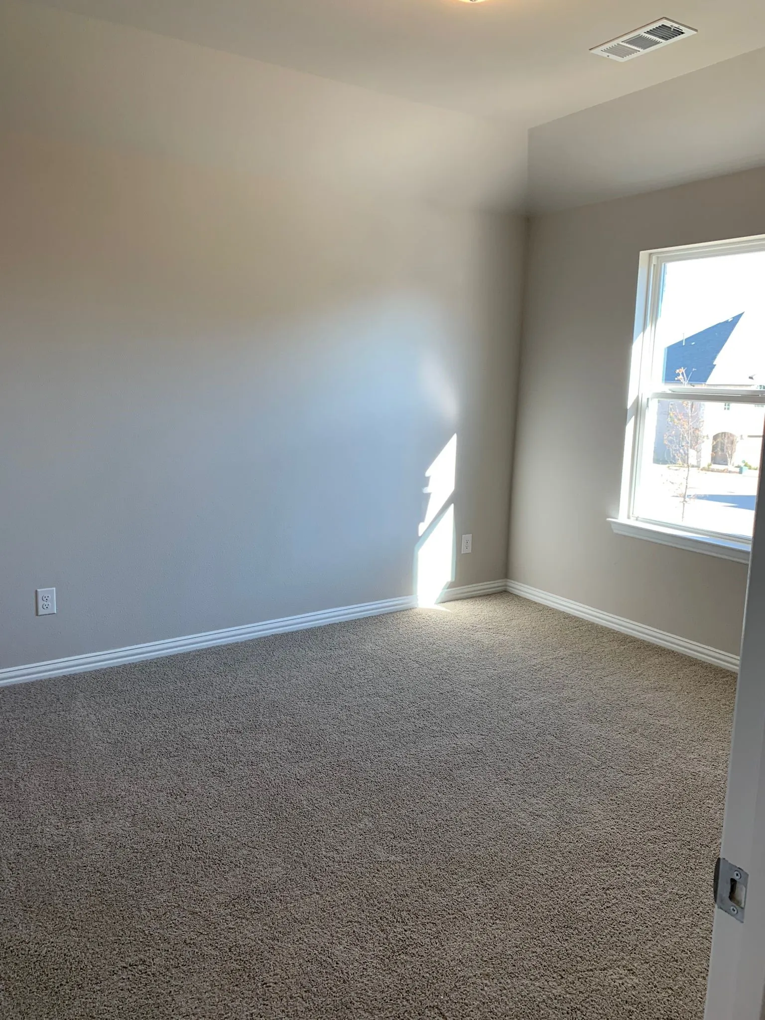 Carpeted flooring, neutral wall paint, white trim, and a window for natural illumination