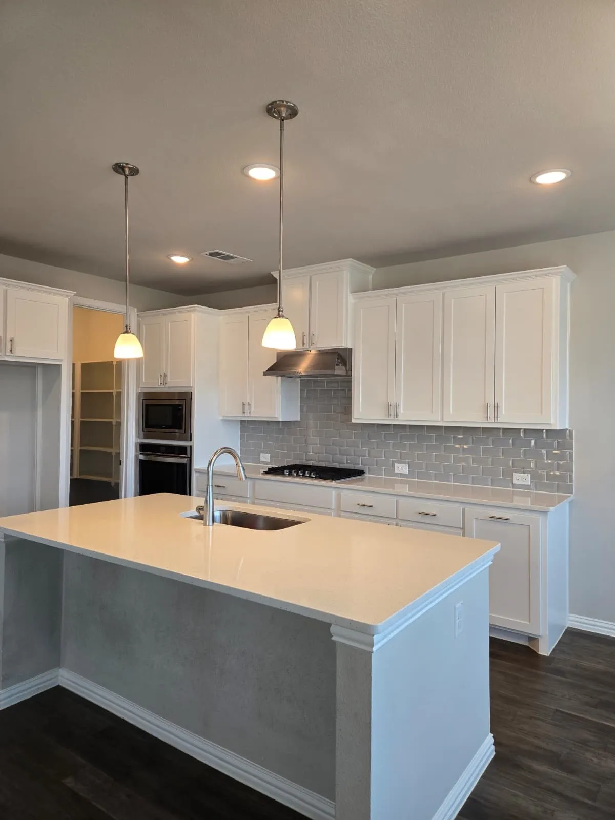Kitchen featuring white cabinetry, light-toned countertops, a subway tile backsplash, and stainless steel appliances