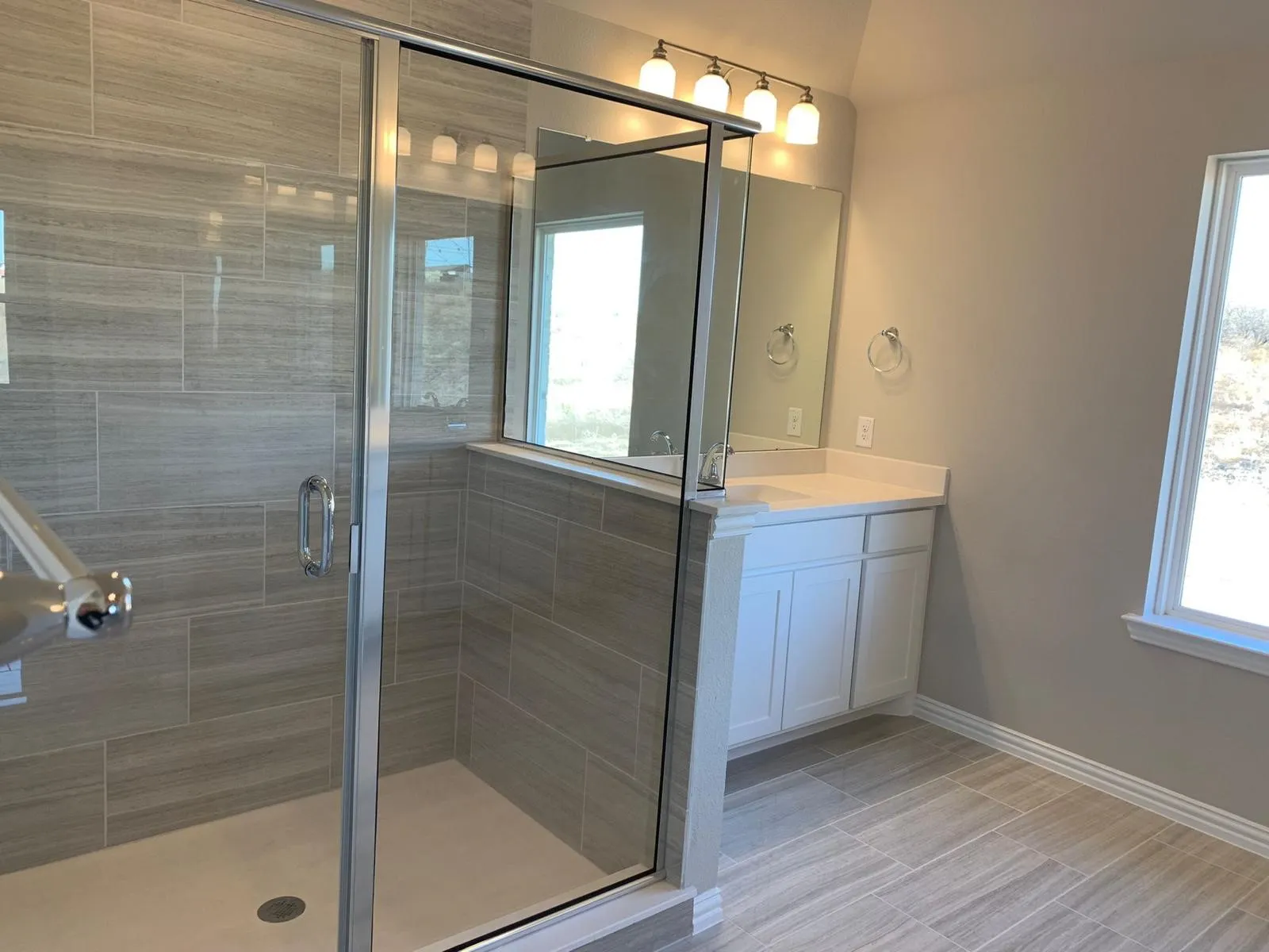 Glass-enclosed shower with gray tiled walls
