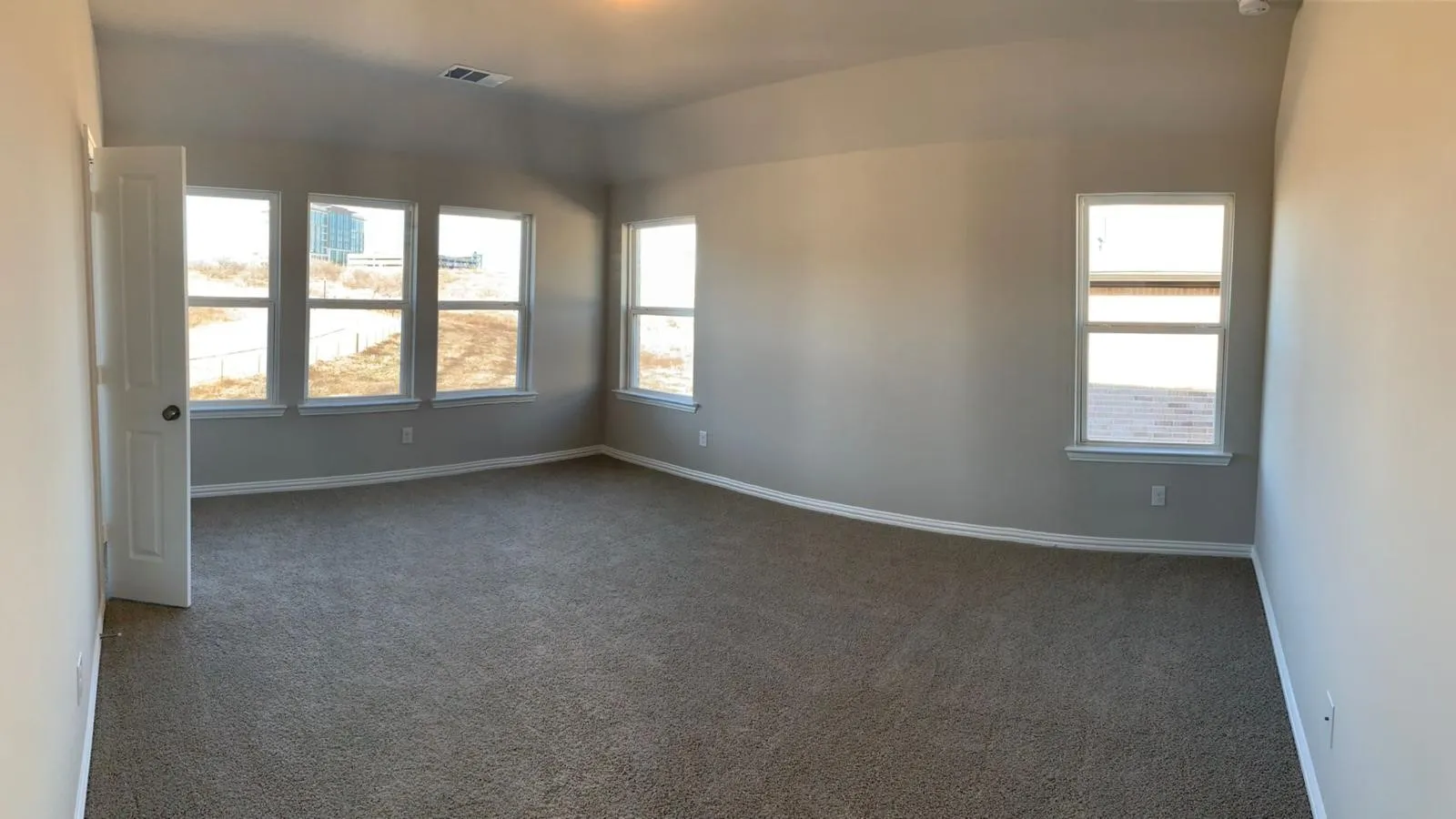 Spacious room with plush carpet, multiple windows, and neutral wall tones