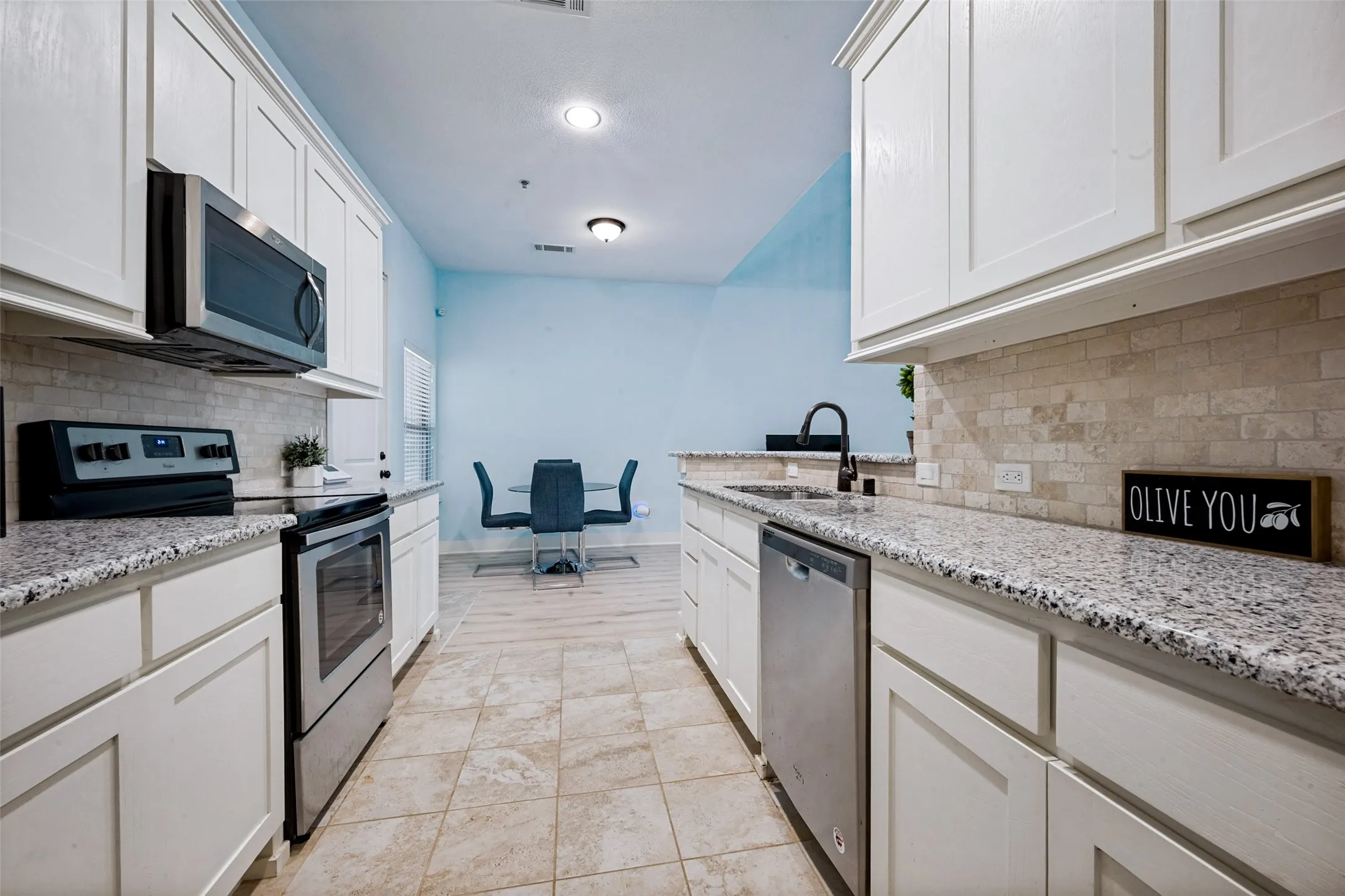 Kitchen featuring white shaker-style cabinetry, stainless steel appliances, granite counter tops, and a subway tile backsplash