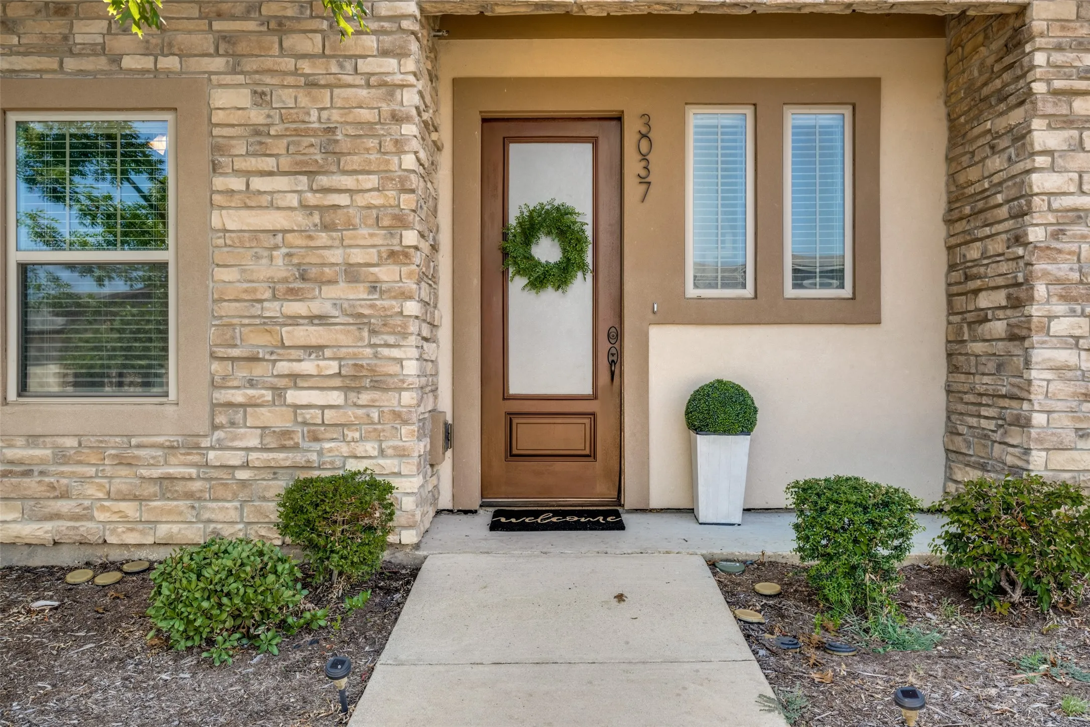 Stone veneer facade with a wood-finish entry door featuring a frosted glass insert