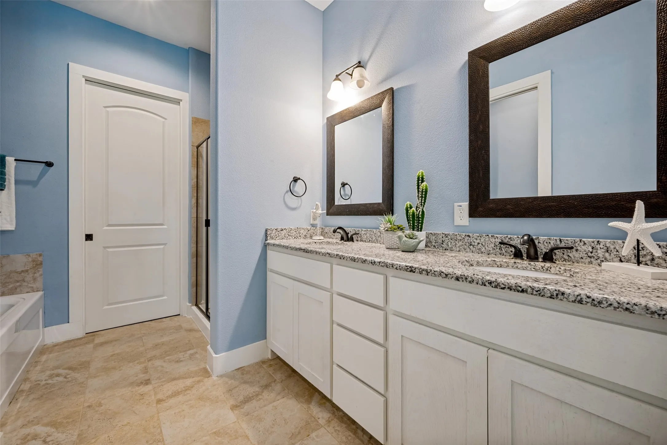 Dual vanity with stone countertops, white shaker-style cabinetry, and individual framed mirrors