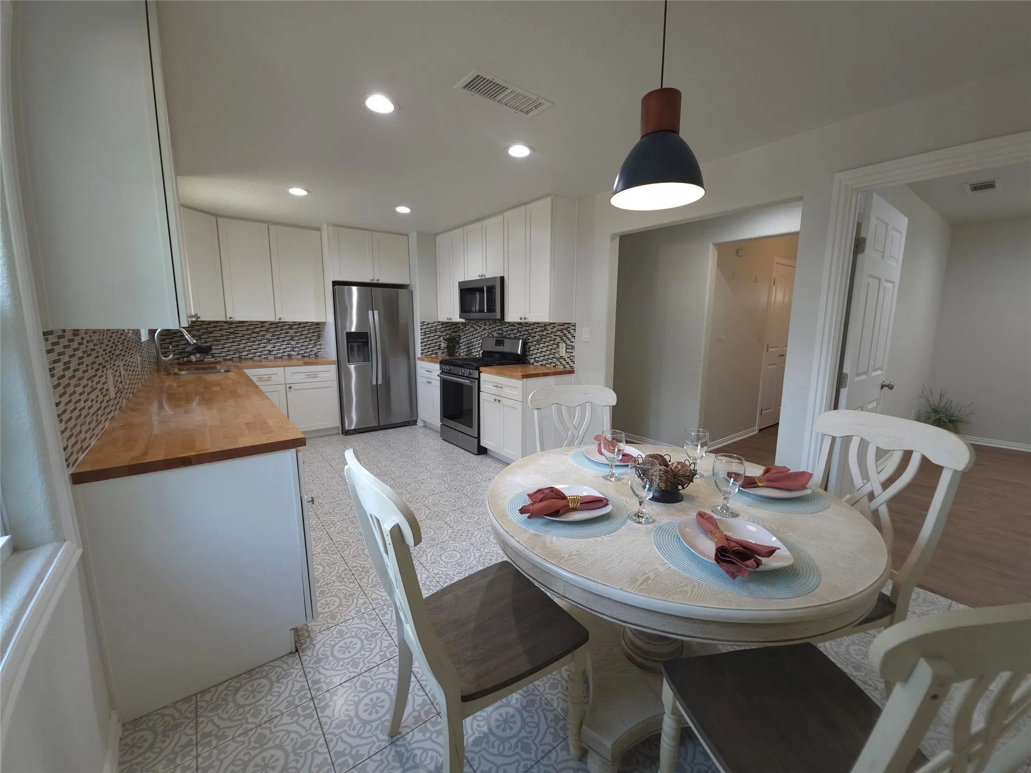 Kitchen features all stainless steel appliances including a refrigerator and gas stove