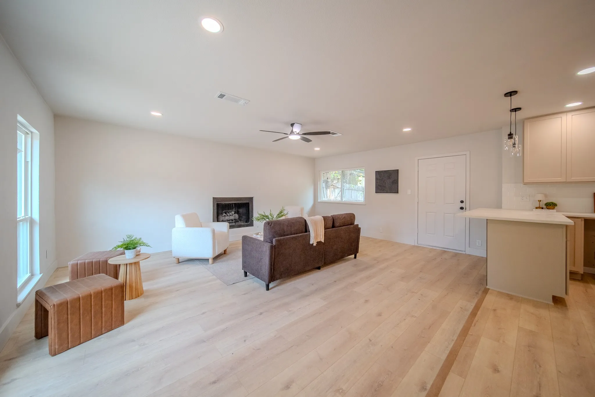 Spacious living area featuring wood-finish flooring, a fireplace, recessed lighting, and an open-concept kitchen with a breakfast bar
