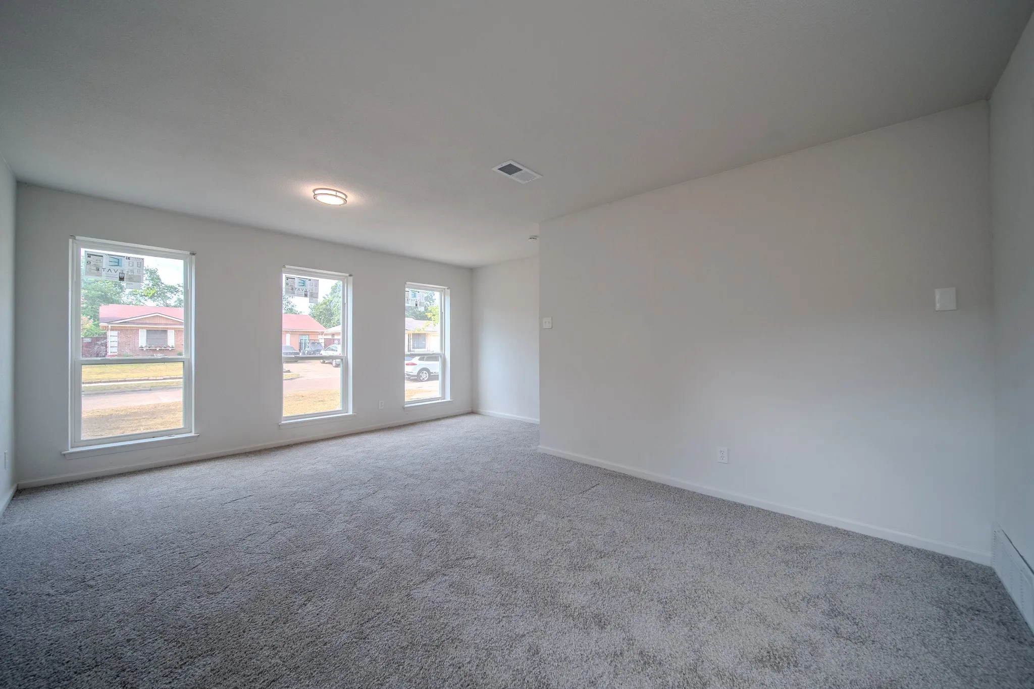 Spacious room with gray carpet, multiple windows, and light gray wall paint