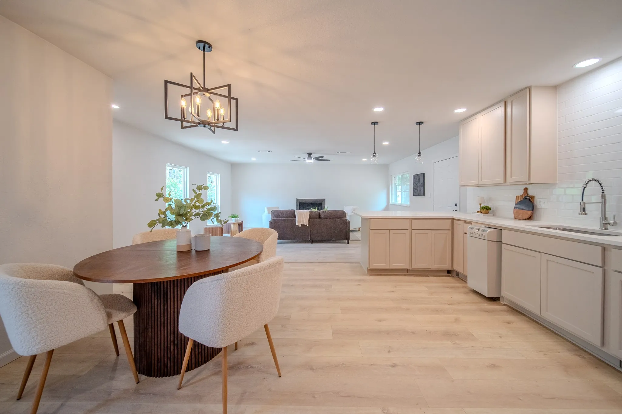Open-concept living space featuring wood-finish flooring, recessed lighting, and a modern geometric chandelier