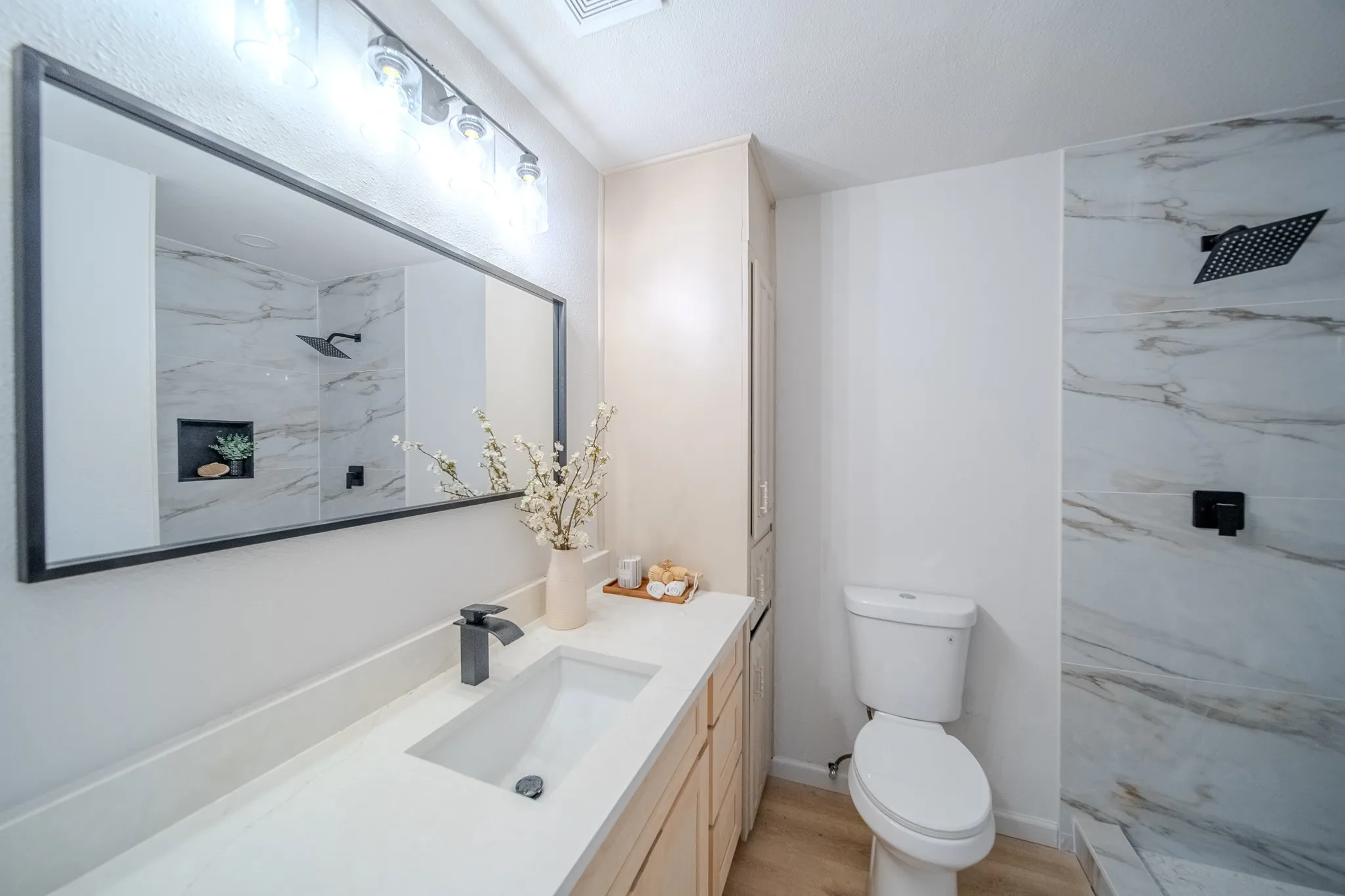 Single vanity with an integrated sink, matte black faucet, and light wood-finish cabinetry