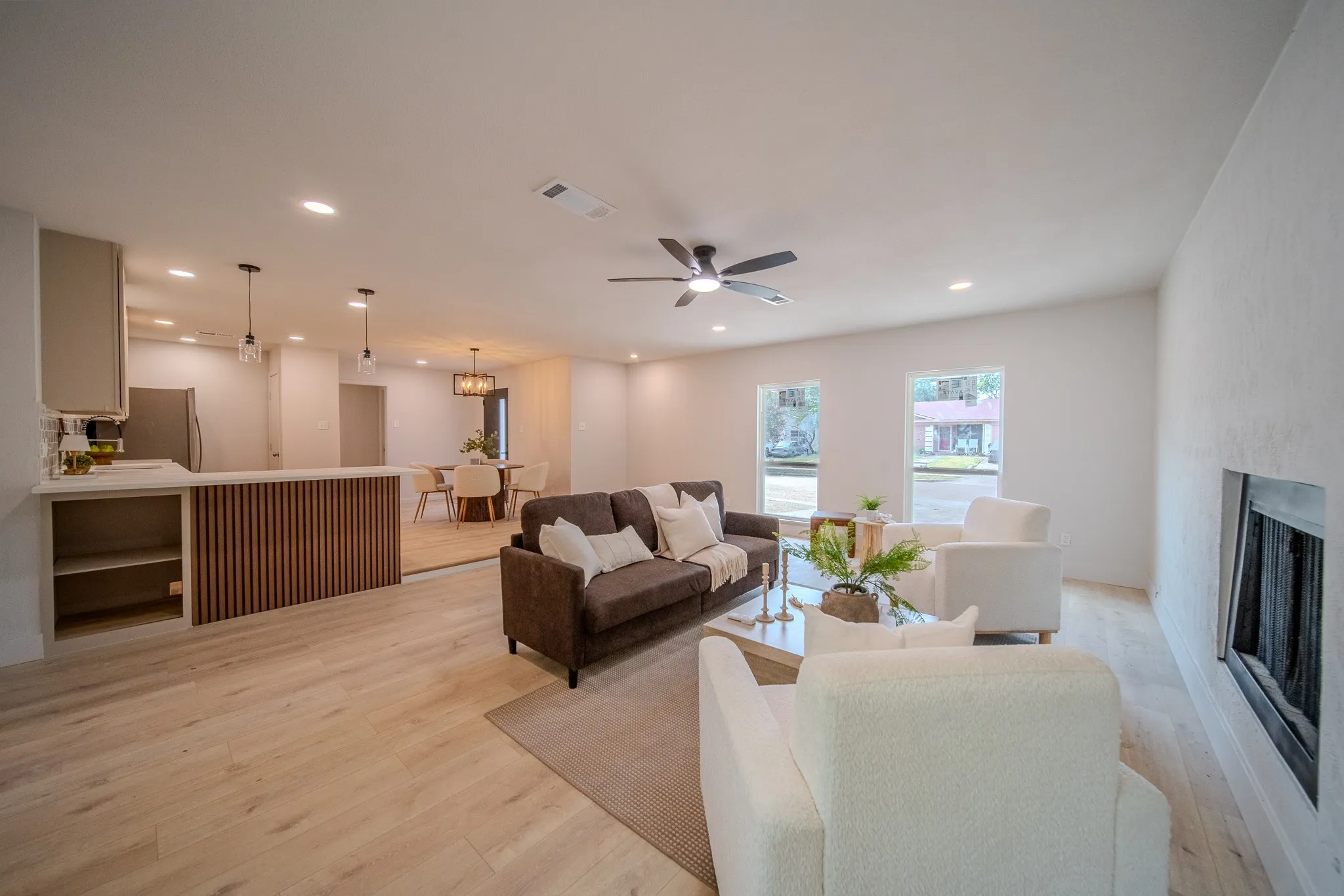 Open-concept living area featuring wood-finish flooring, recessed lighting, and a built-in fireplace